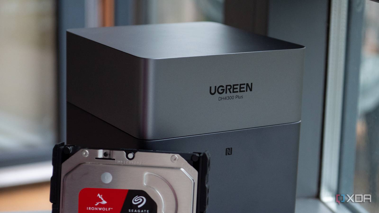 Grey UGREEN DH4300 Plus enclosure with a Seagate IronWolf hard drive partially inserted. Text on device reads \
