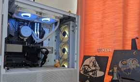 A white gaming PC with RGB fans next to a curtain and some paintings