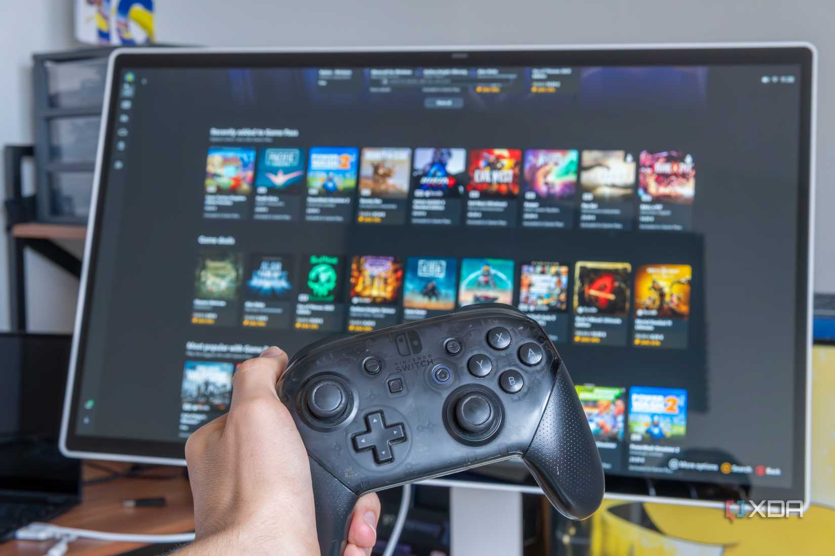 一只手在屏幕前握着 Nintendo Switch Pro 控制器,展示 Windows 11 中的全屏游戏体验