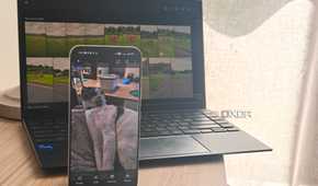 immich on a smartphone in front of a laptop