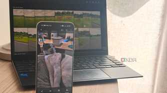 immich on a smartphone in front of a laptop