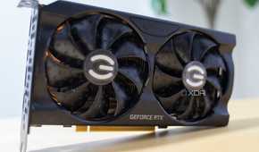 A graphics card with a black shroud standing on its side on a yellow table.