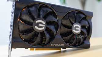 A graphics card with a black shroud standing on its side on a yellow table.