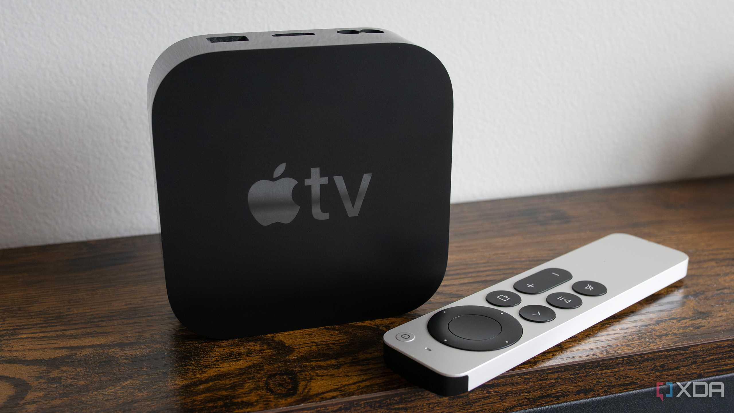 The Apple TV 4K sitting on a table beside the Siri Remote
