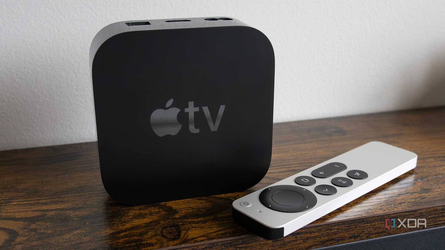 The Apple TV 4K sitting on a table beside the Siri Remote