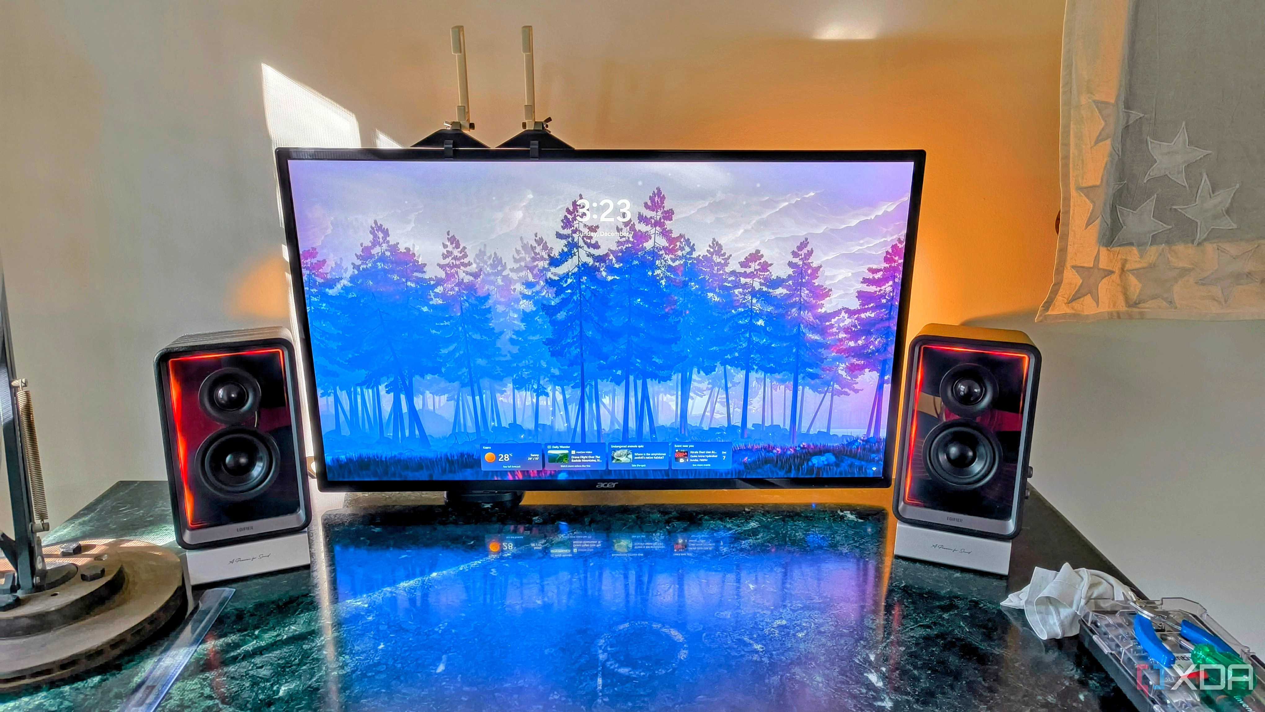 Black and silver speakers flanking a computer monitor on a shiny marble desk