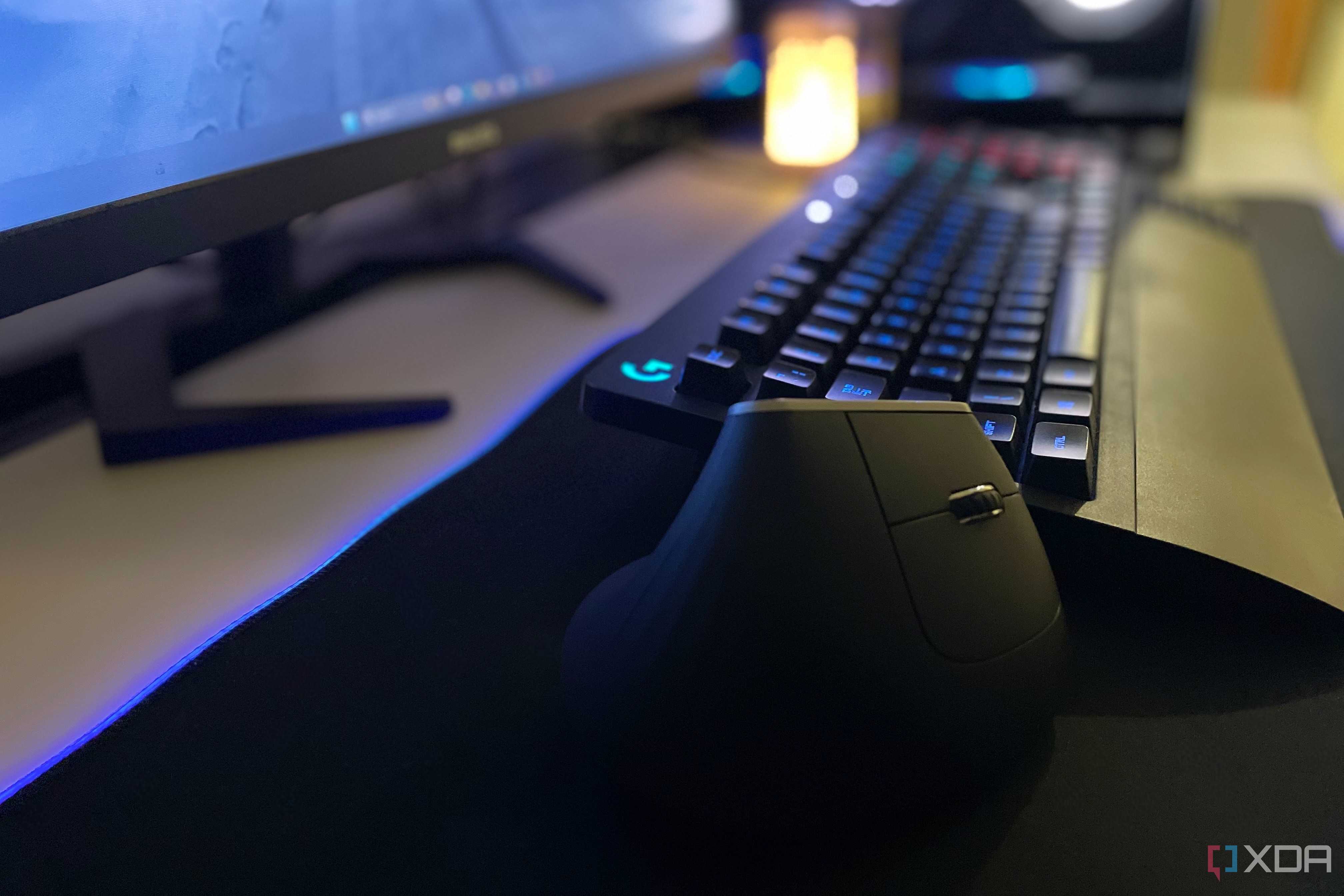 An image of an ergonomic mouse lying beside a keyboard on a deskmat.