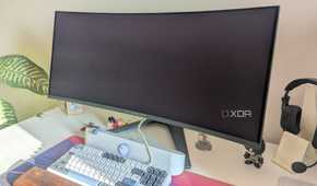 An turned-off ultrawide monitor on a white desk next to a keyboard and soundbar