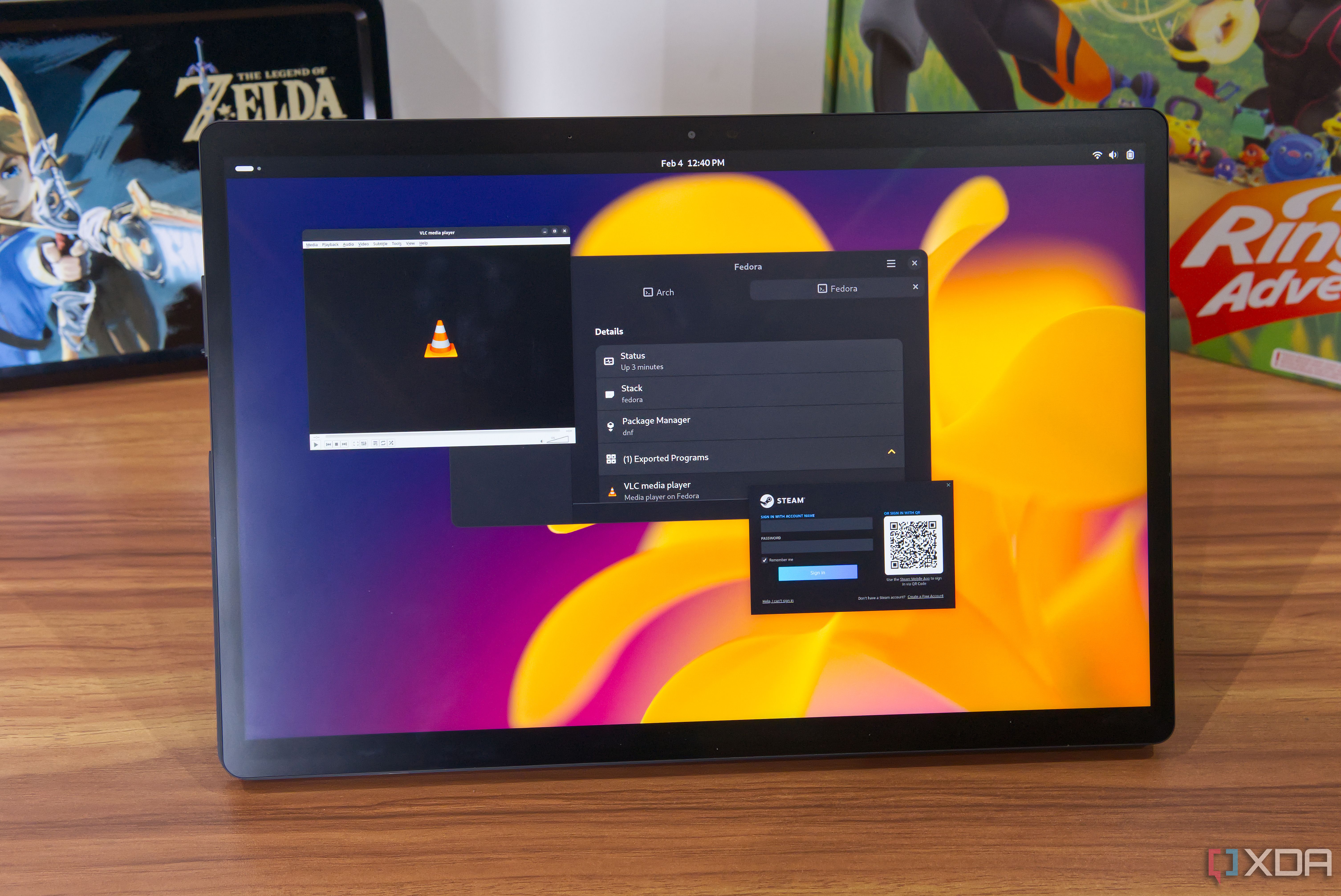 A tablet showing a Vanilla OS desktop with an Apx app showing information about the subsystem. Along with Steam for Arch, VLC for Fedora is also open