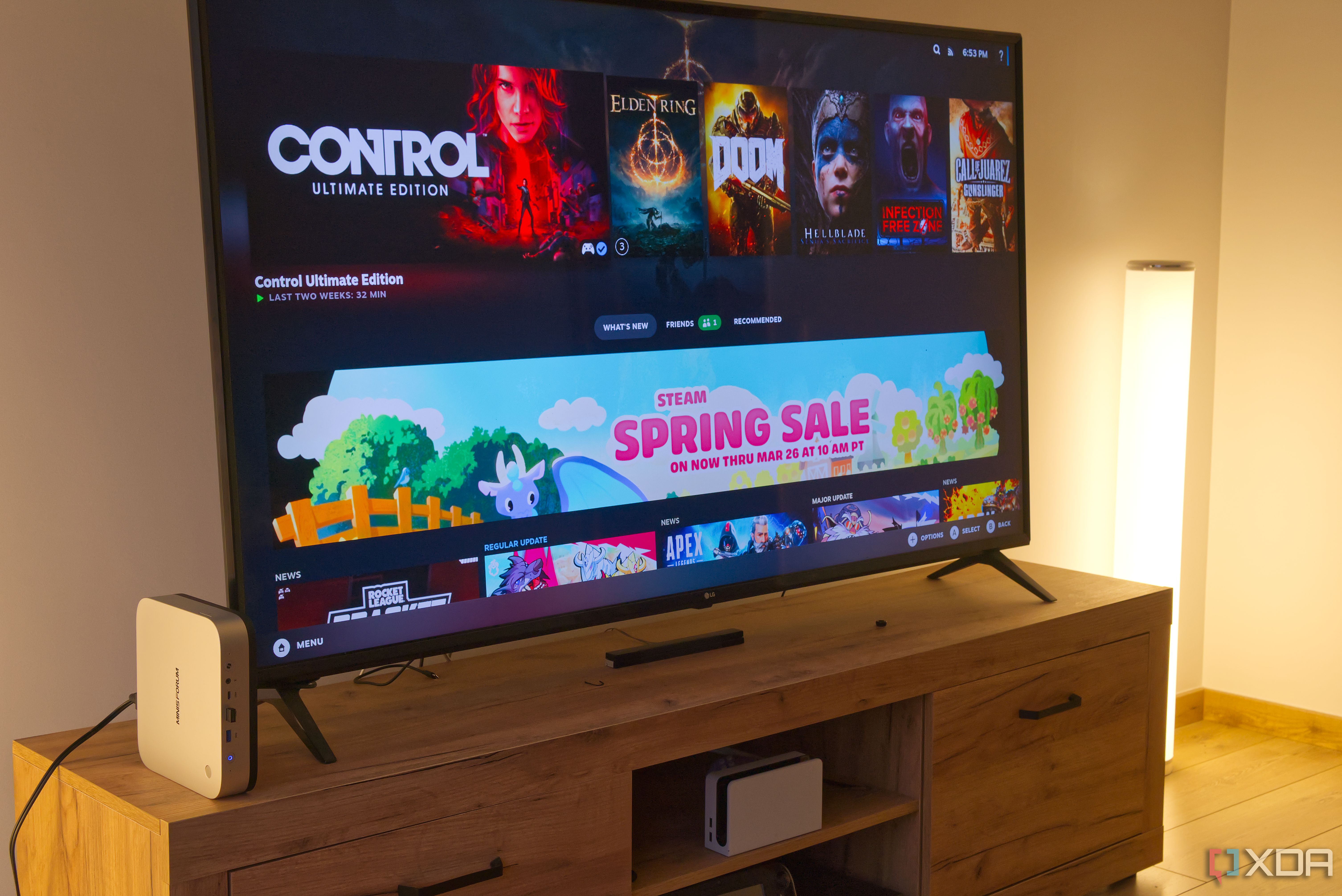 A TV displaying the Steam Gaming Mode UI on Bazzite, with a mini PC next to it