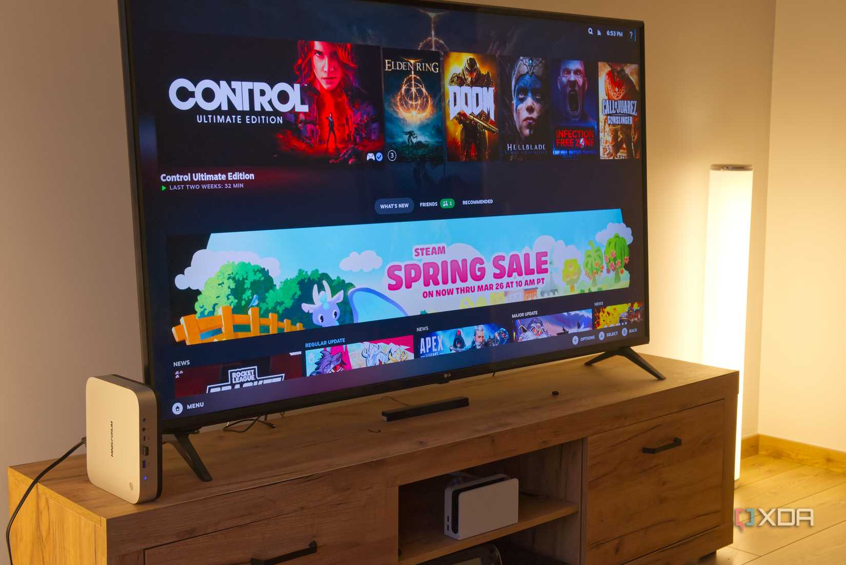 A TV showing the Steam Gaming mode UI in Bazzite, with a mini PC next to it