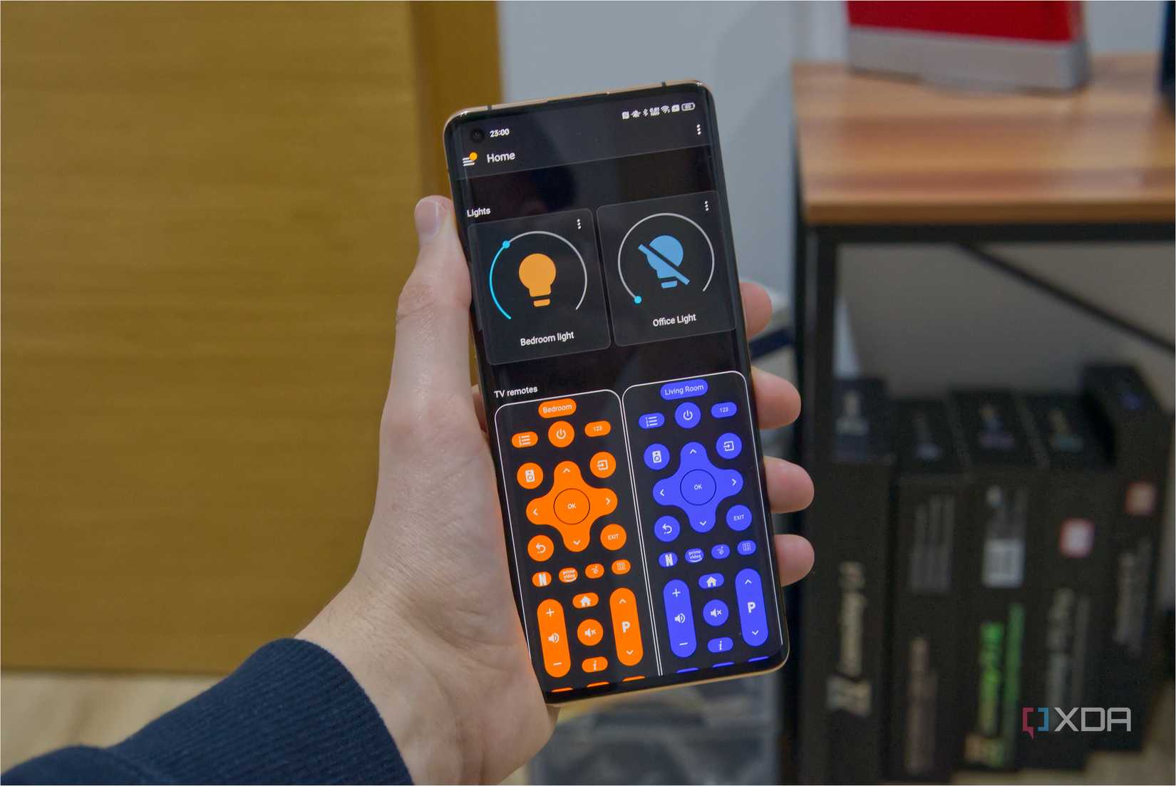 A phone showing a Home Assistant panel with lighting controls and TV remotes