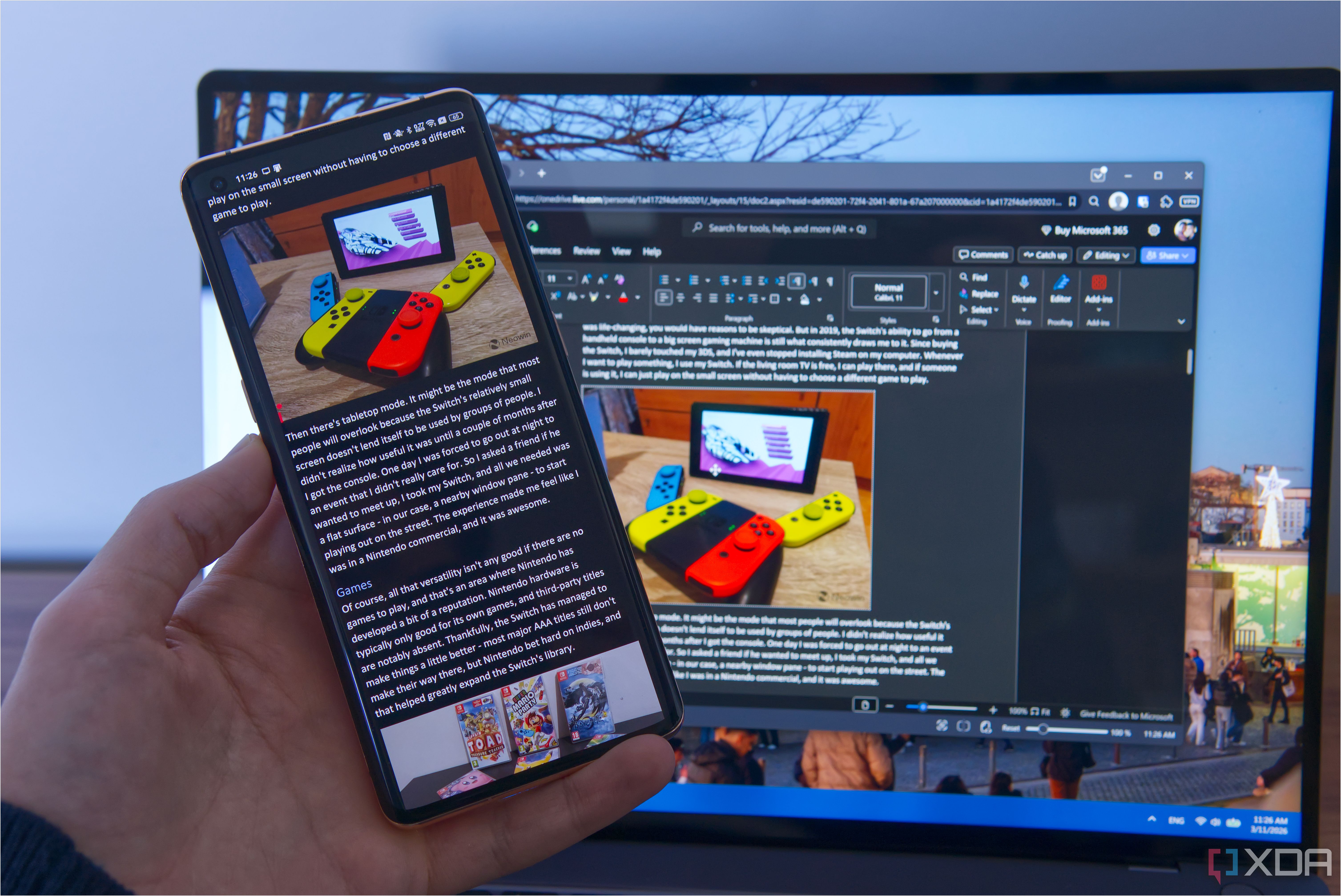 A phone running Microsoft Word with a computer in the background editing the same document