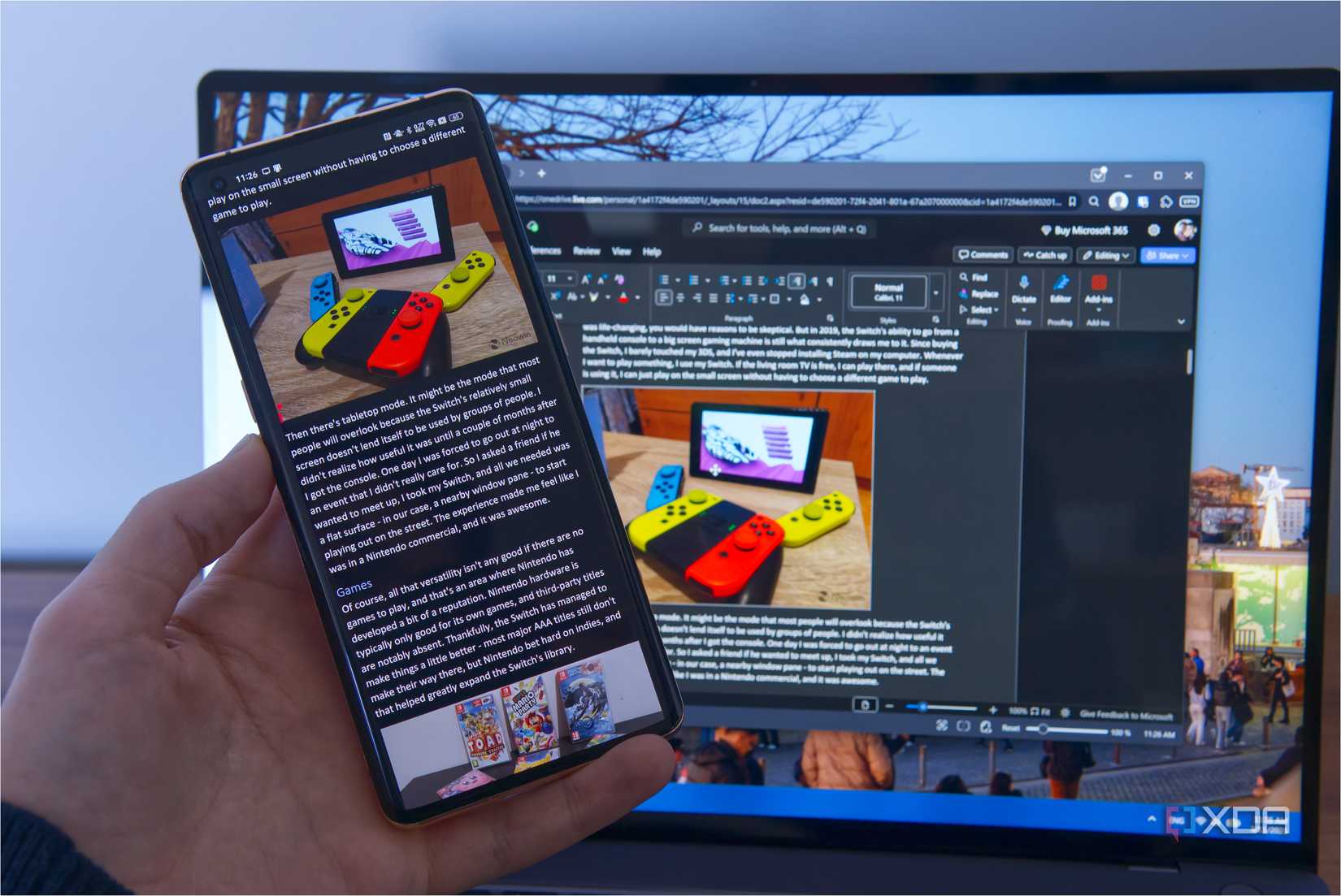 A phone running Microsoft Word with a computer in the background editing the same document