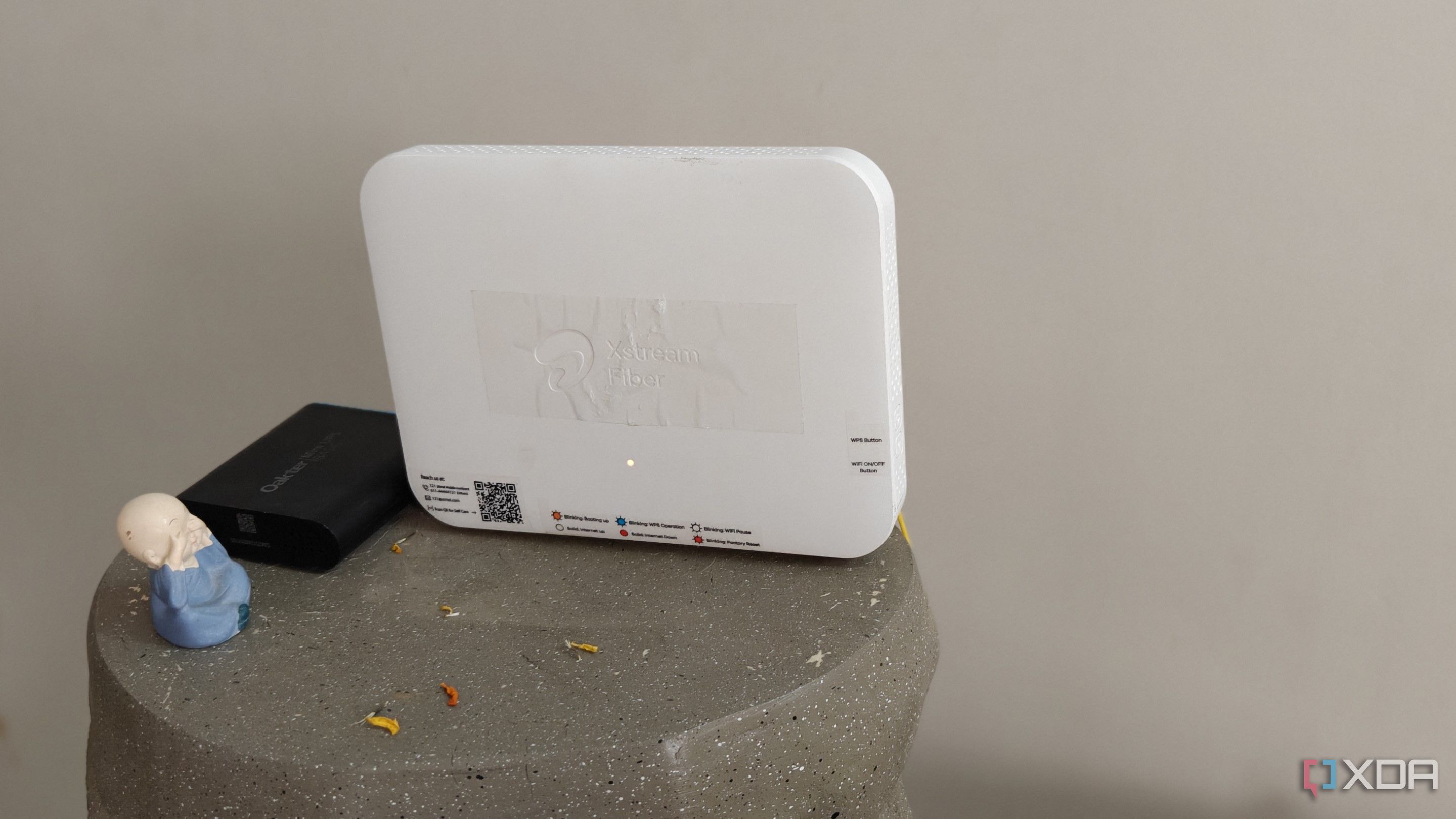 A white Wi-Fi 6 router with a black mini UPS on a grey surface