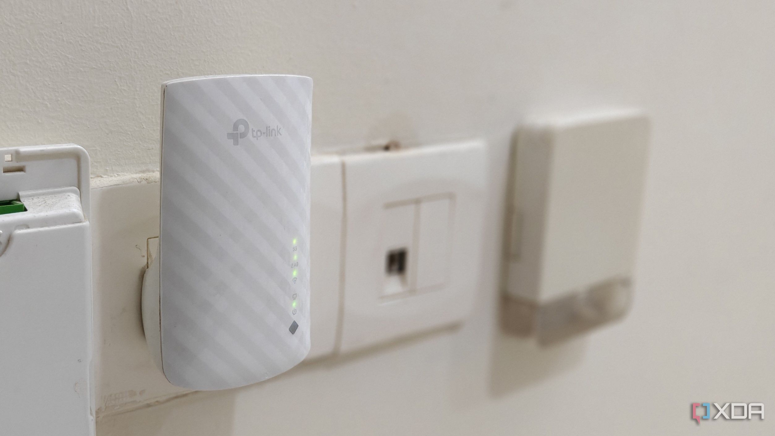 A white Wi-Fi extender plugged into a wall outlet
