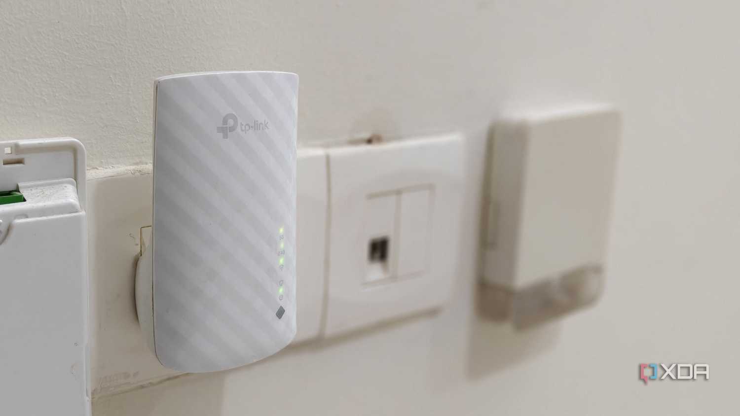A white Wi-Fi extender plugged into a wall outlet