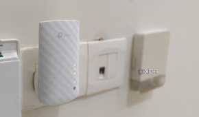 A white Wi-Fi extender plugged into a wall outlet