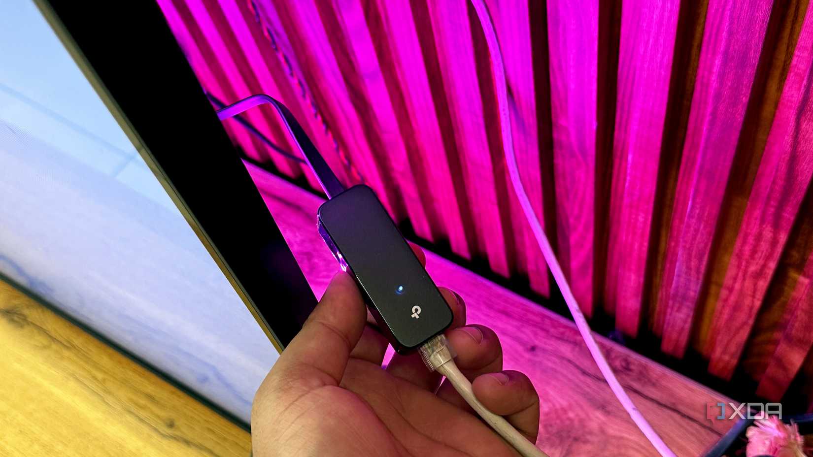 LAN cable connected to a USB-to-Ethernet 3.0 gigabit adapter behind a TV.