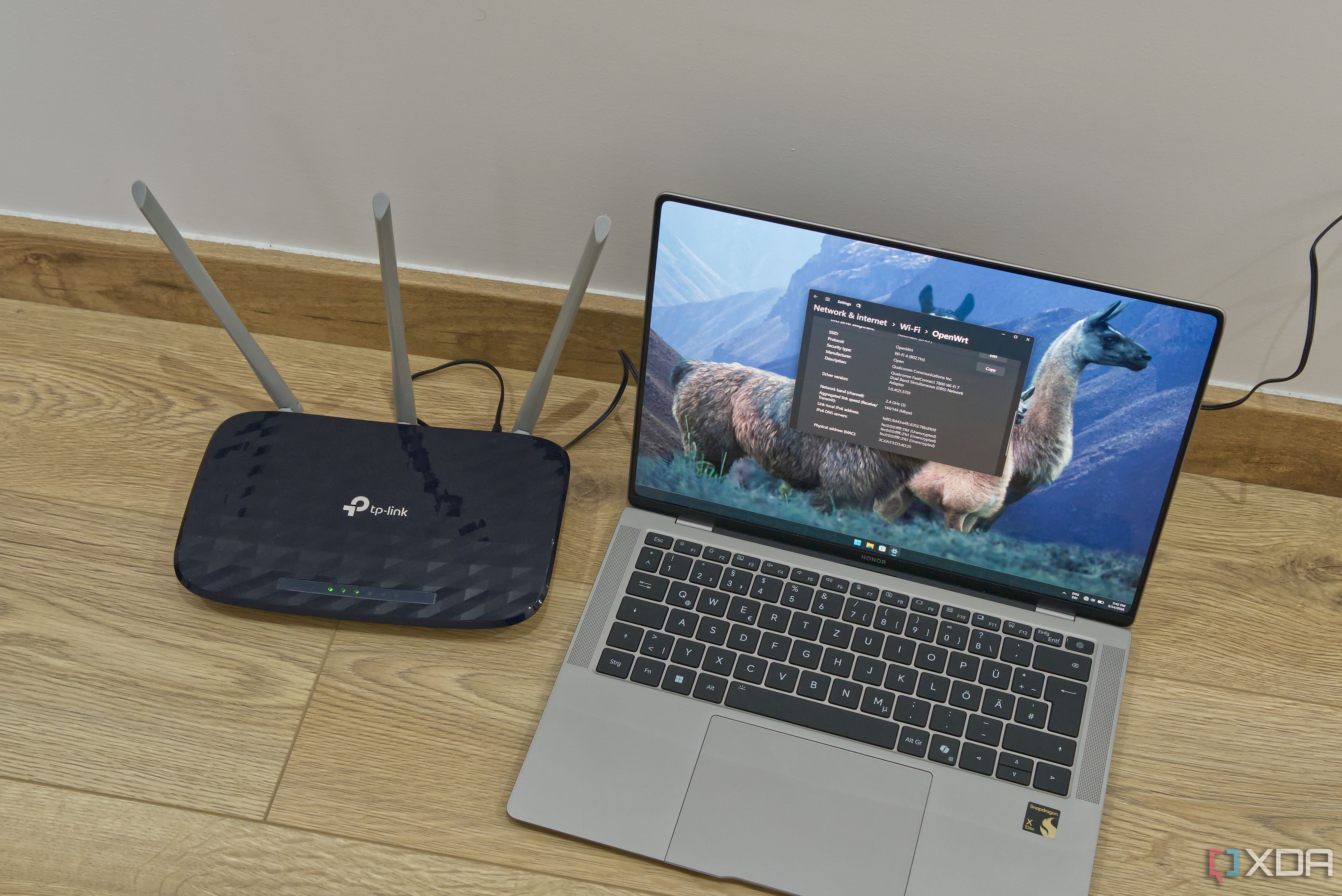 A laptop next to a router used as a Wi-Fi extender