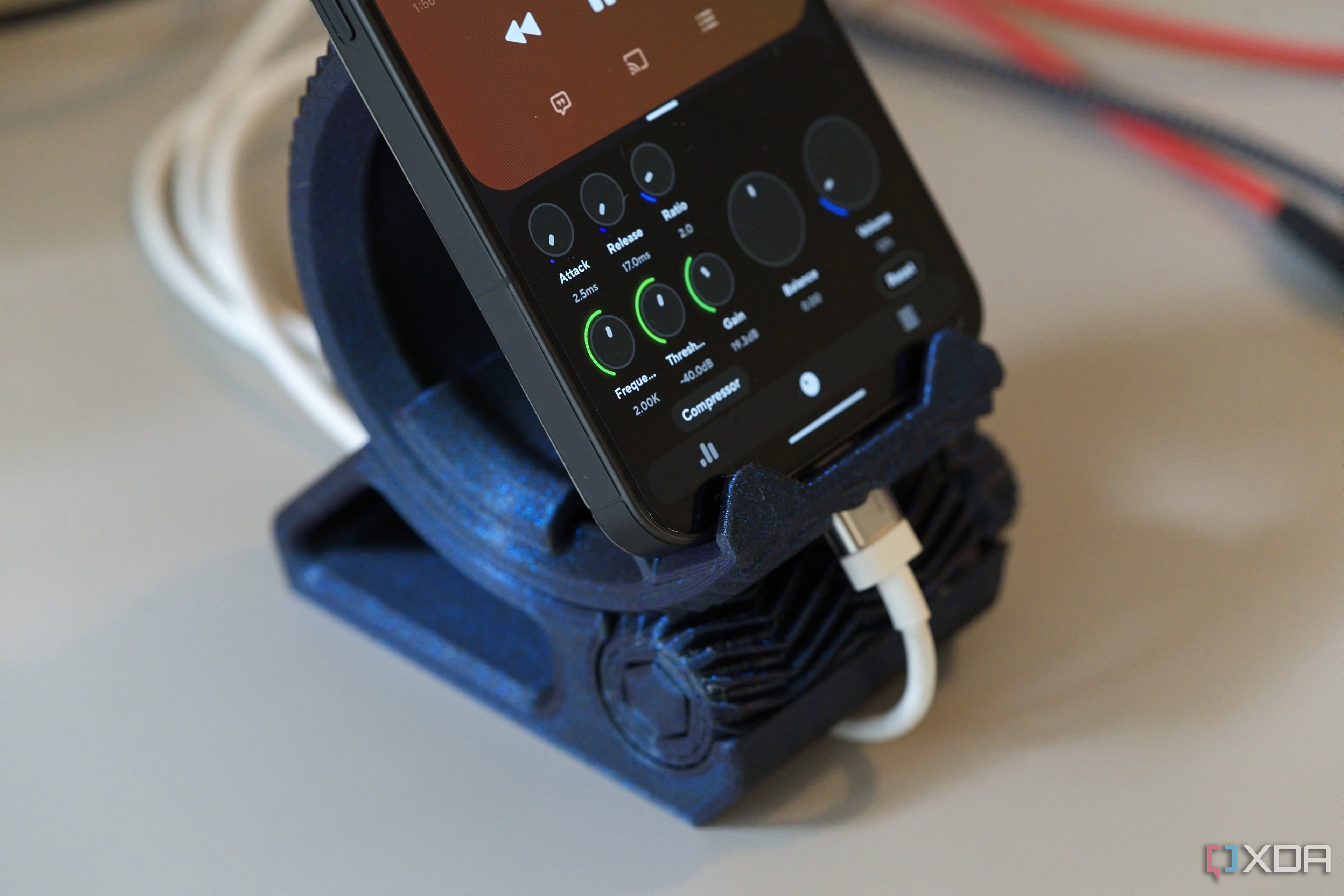 Blue circular 3D printed stand holding a phone with a cable plugged in.
