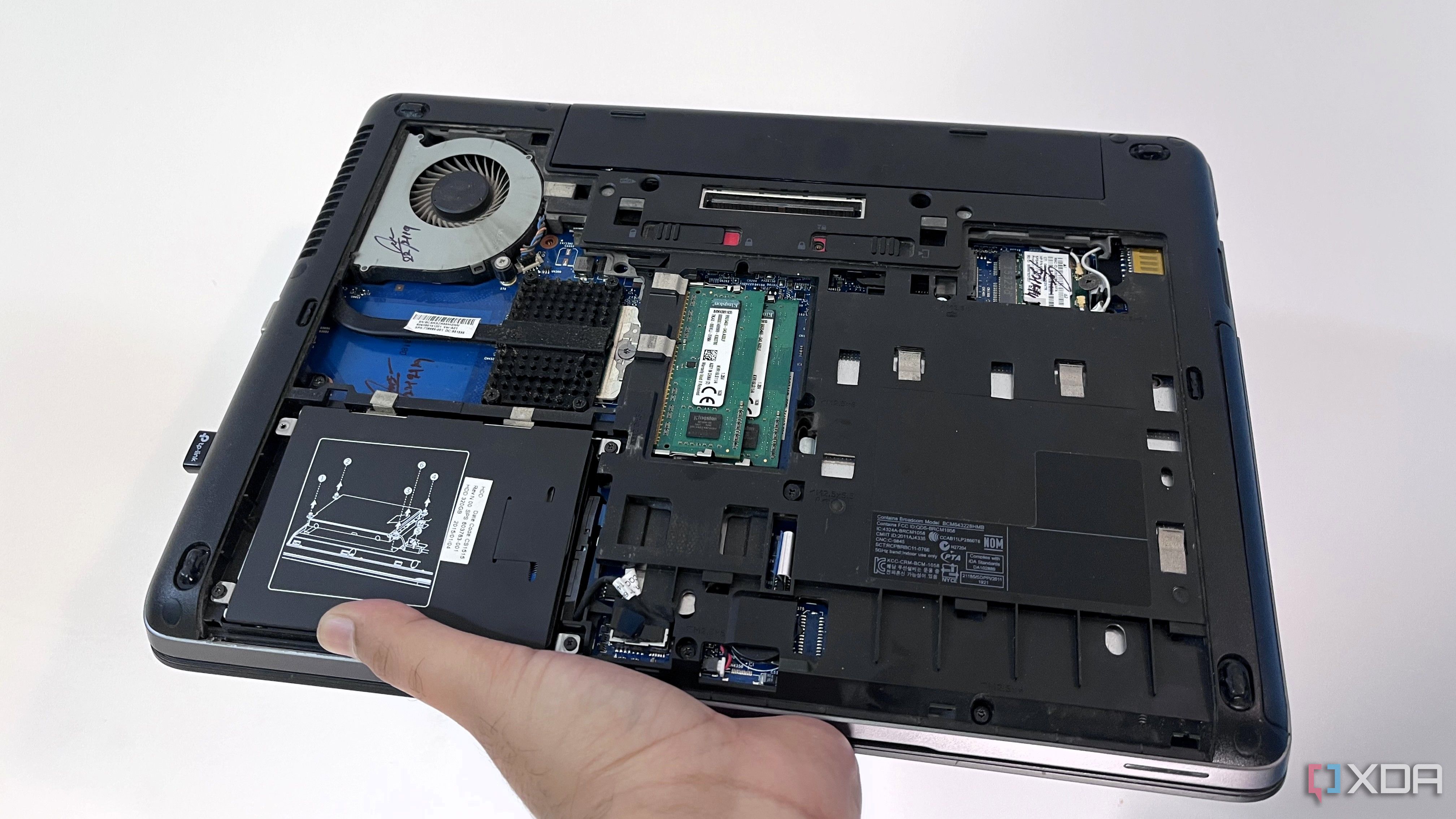 holding HP ProBook 640 G1 with back panel removed against a white background