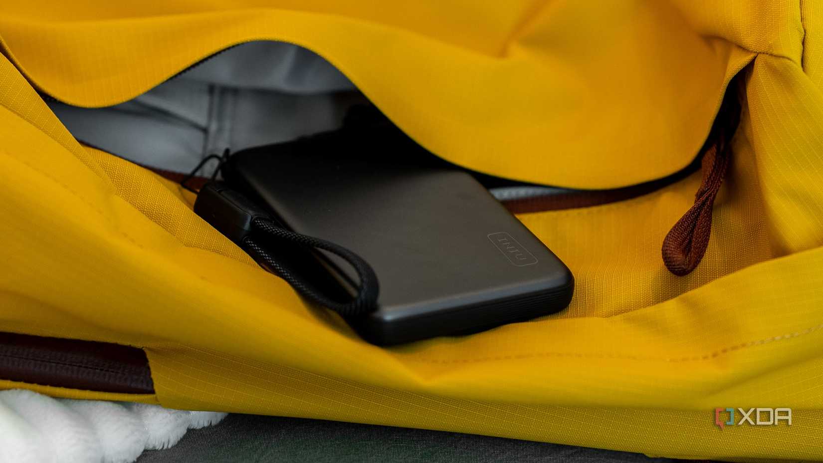 The INIU SnapGo Air Power Bank peeking out from the yellow pocket of a sports bag