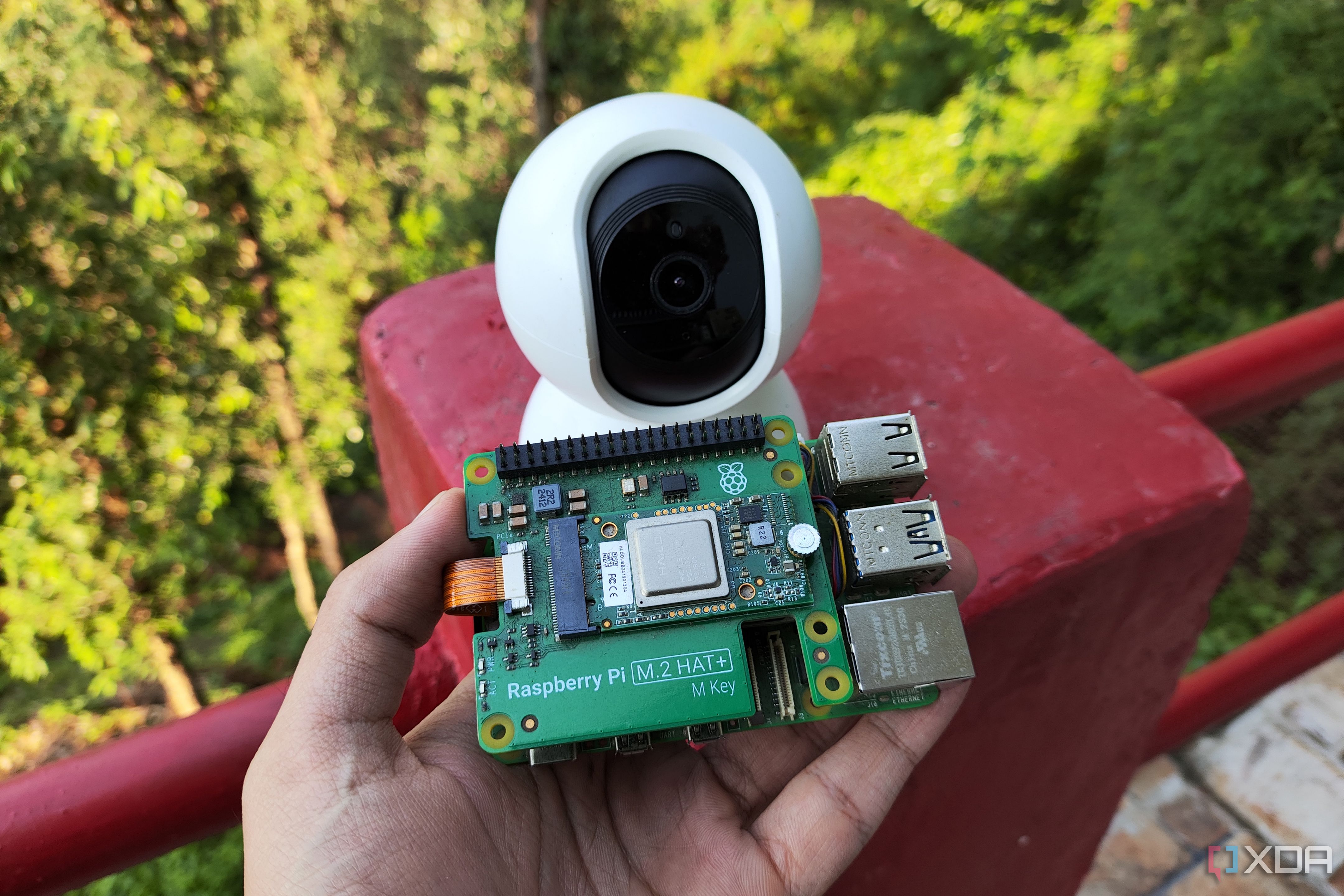 A person holding a Raspberry Pi 5 armed with the AI HAT in front of a security camera