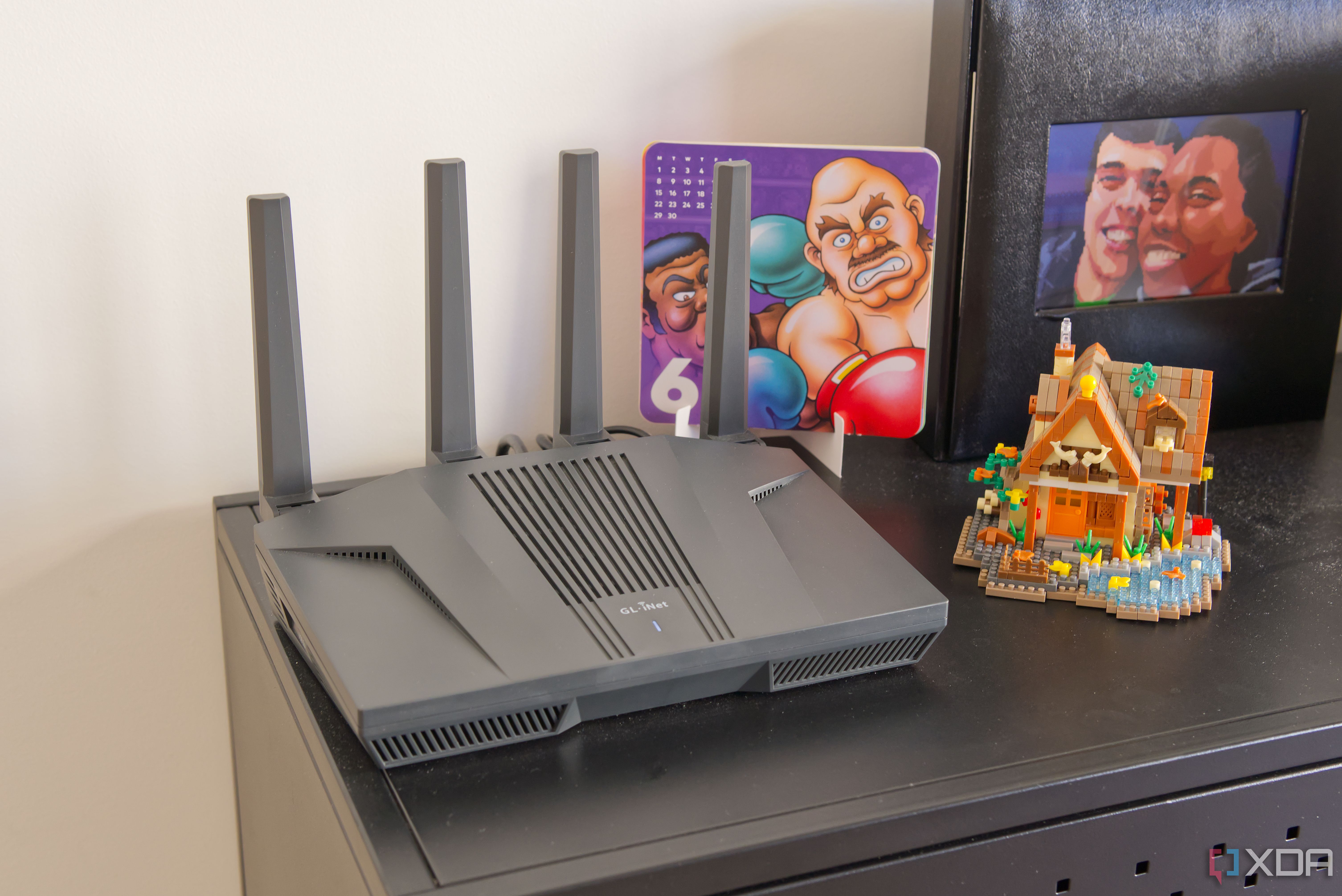 A Wi-Fi router standing on a black surface with some colorful objects around it