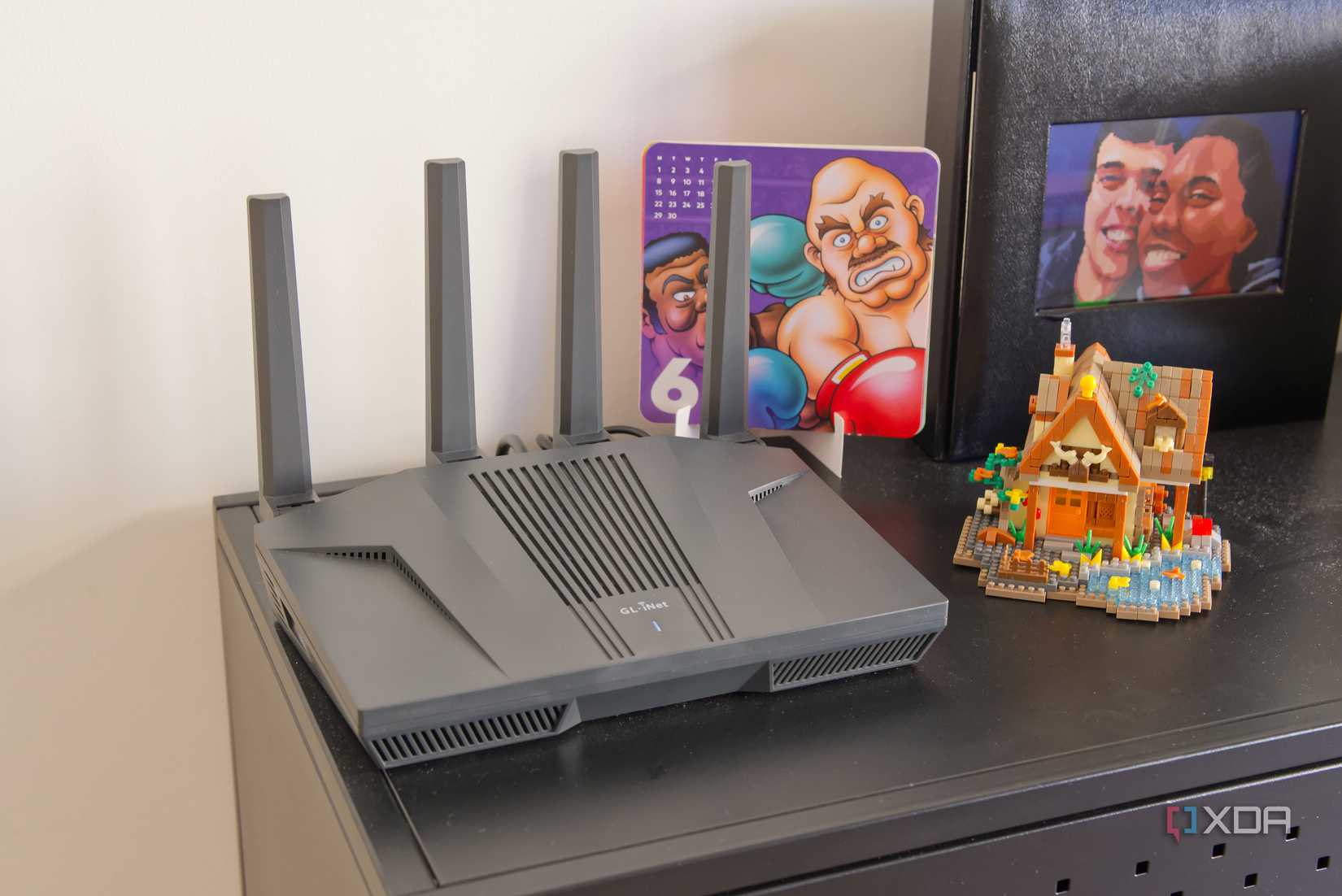 A Wi-Fi router standing on a black surface with some colorful objects around it