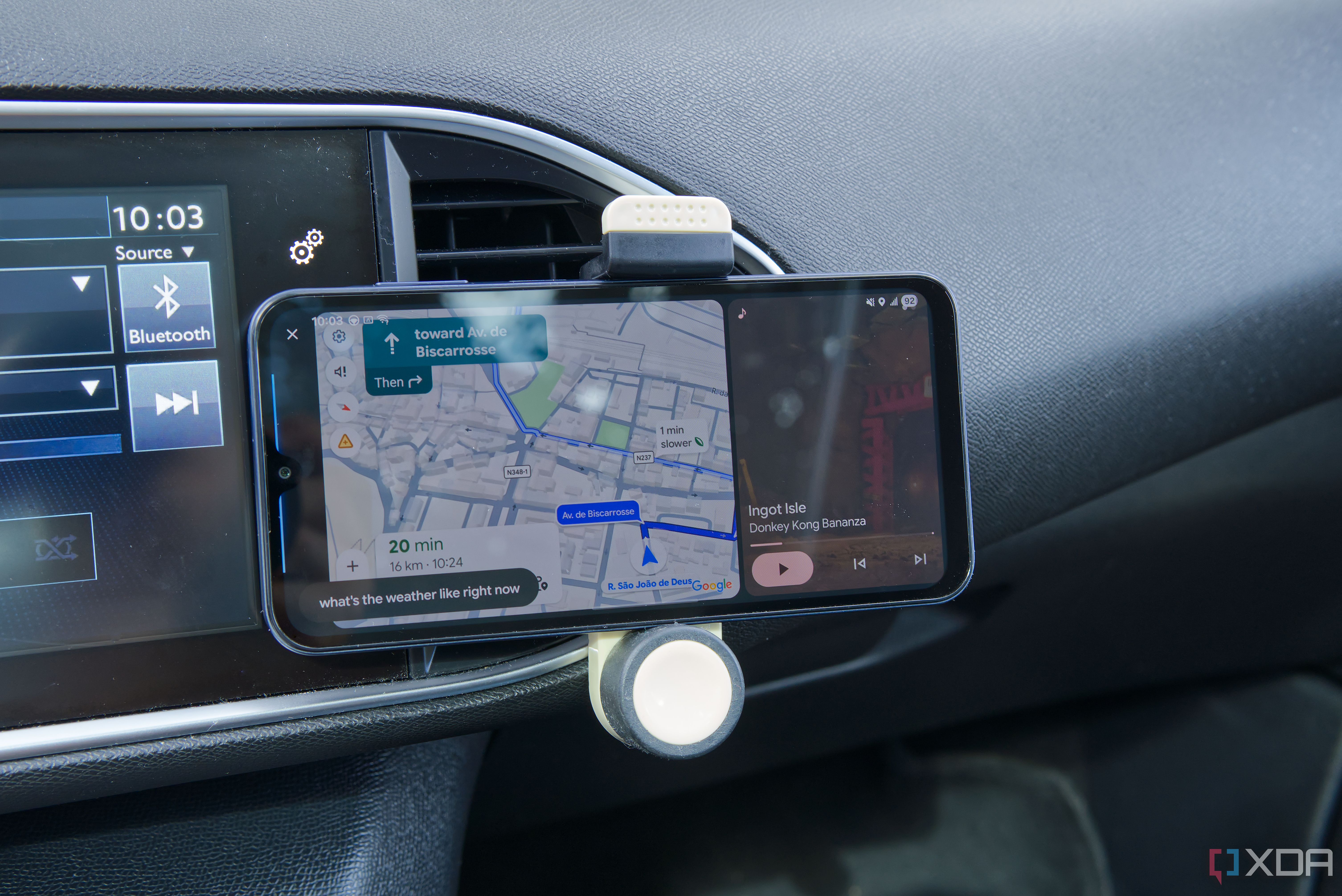 An Android phone showing the ANdroid Auto UI with Google Maps and Nintendo Music open side by side, as well as voice prompt showing the text "what's the weather like rioght now?"