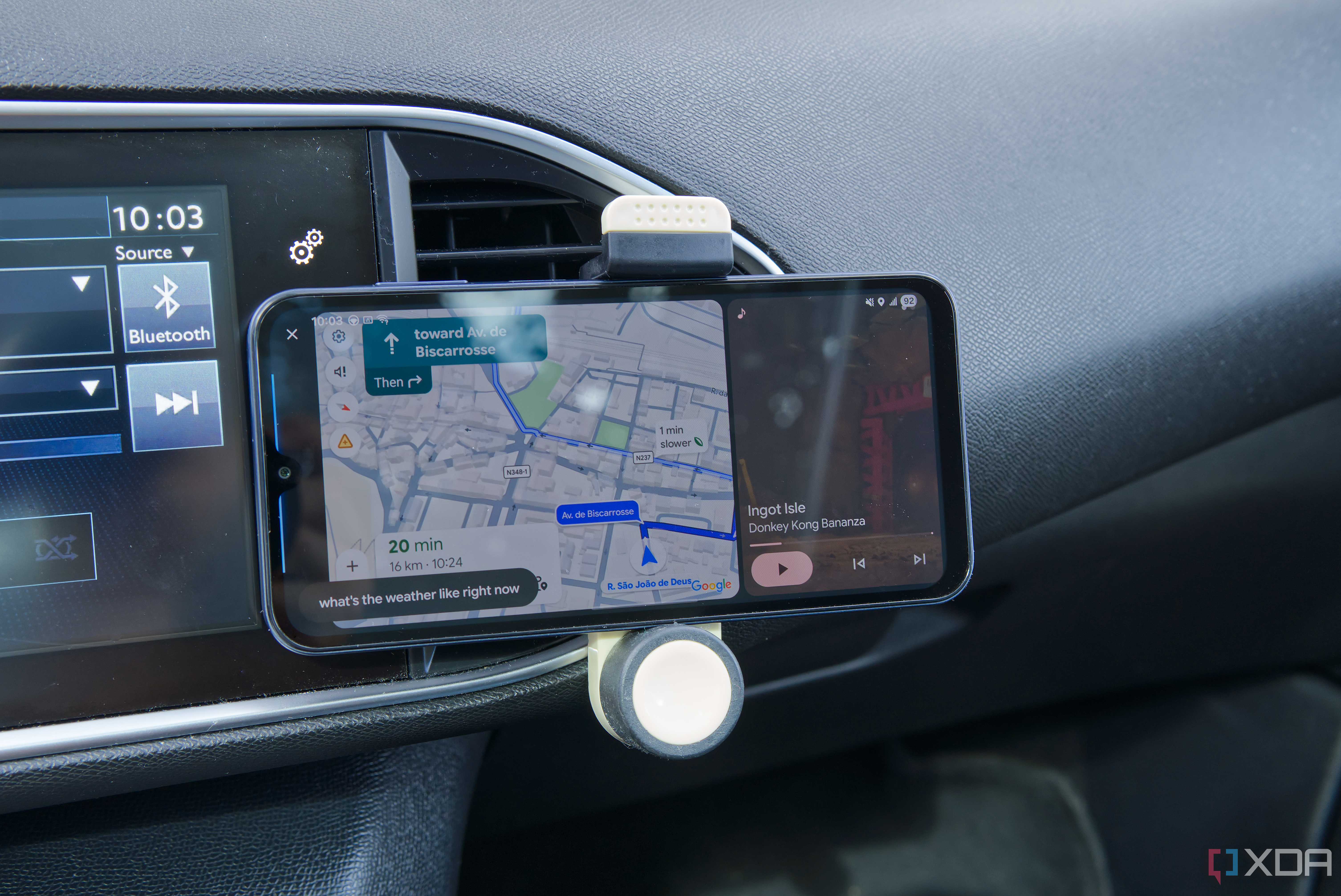 An Android phone showing the ANdroid Auto UI with Google Maps and Nintendo Music open side by side, as well as voice prompt showing the text "what's the weather like rioght now?"