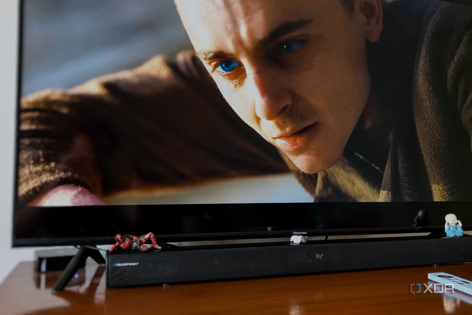A smart TV connected to Apple TV and a black soundbar on a brown desk