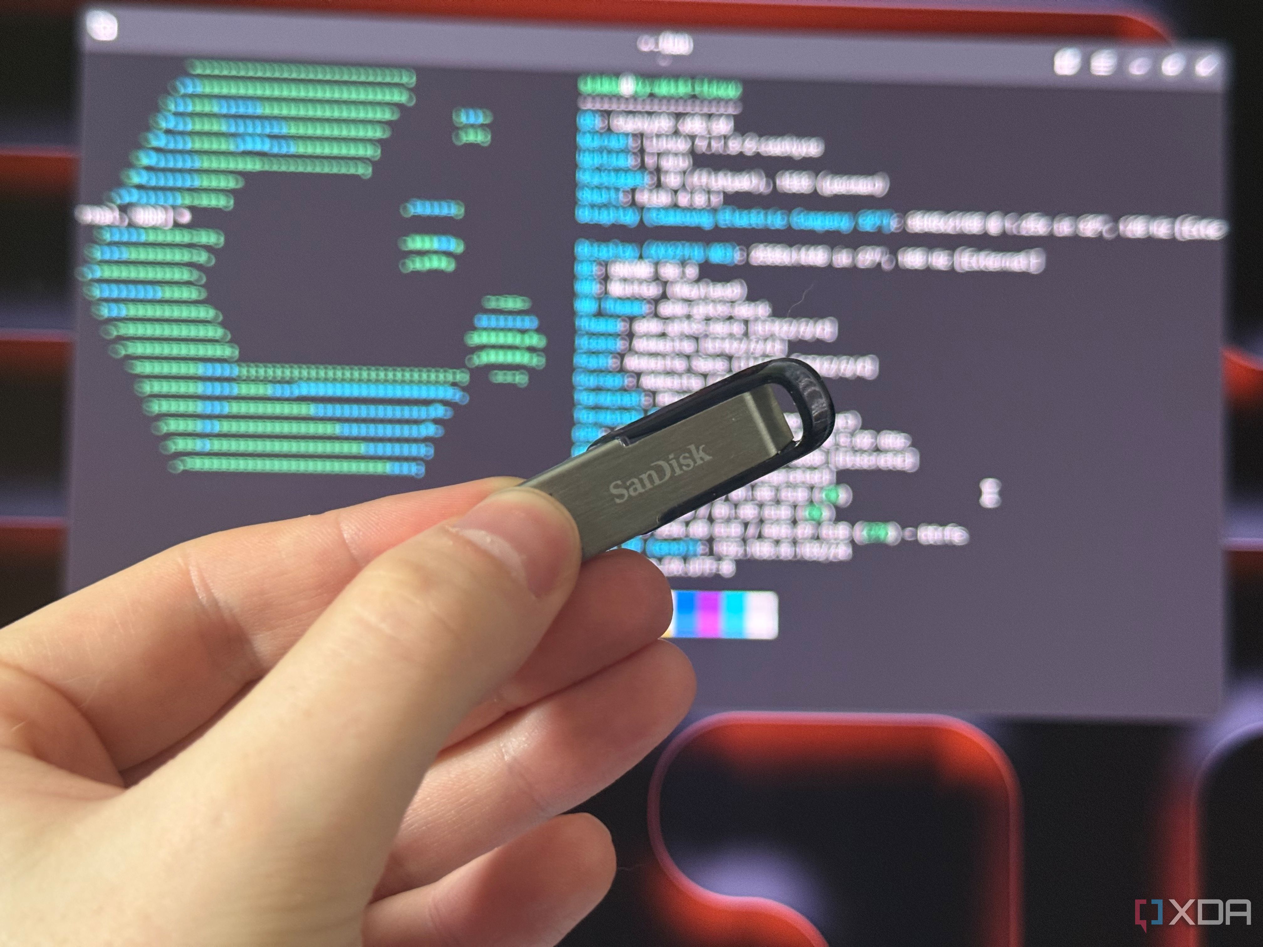 a sandisk USB drive held in front of a monitor showing cachyos