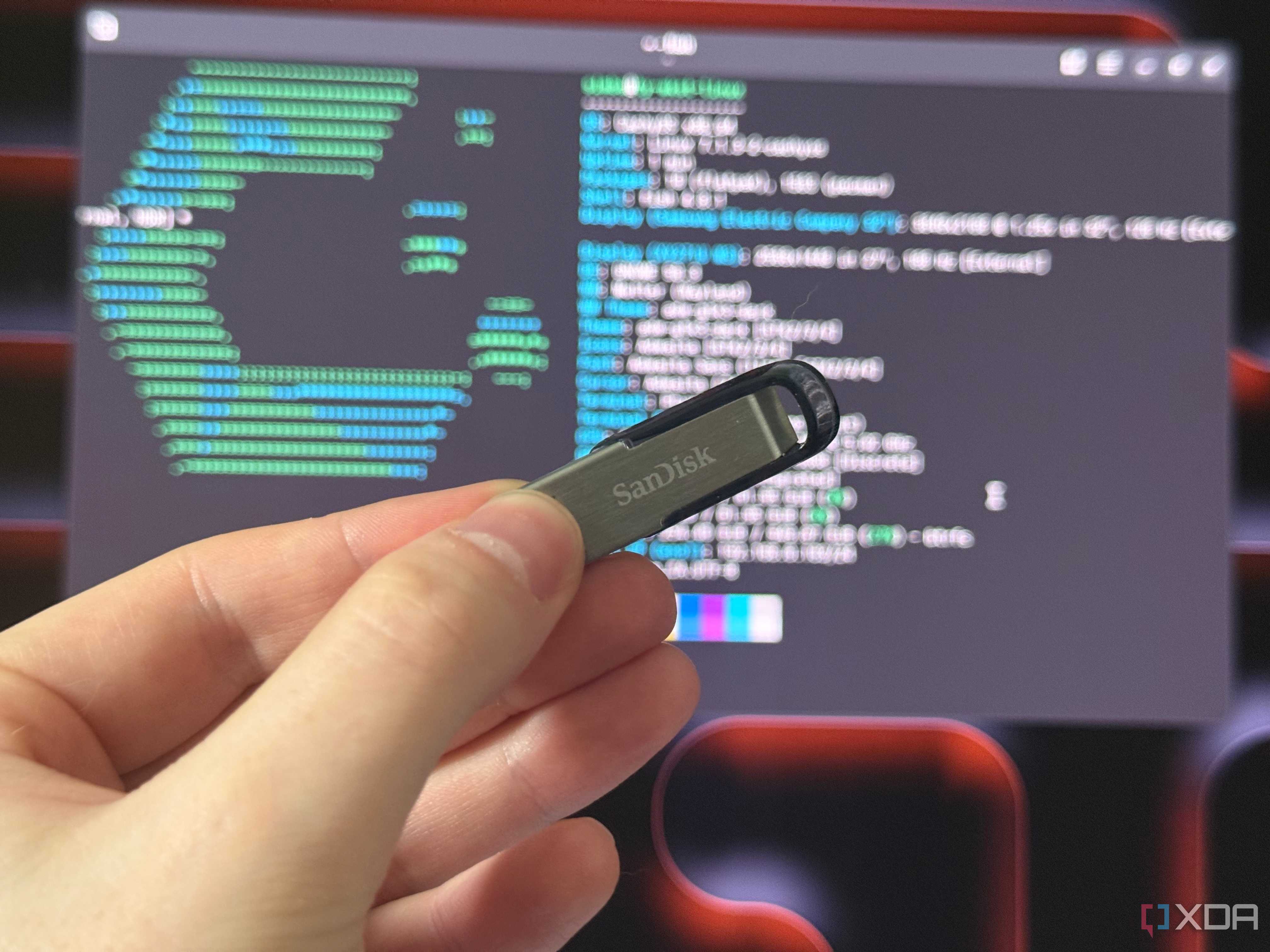 a sandisk USB drive held in front of a monitor showing cachyos