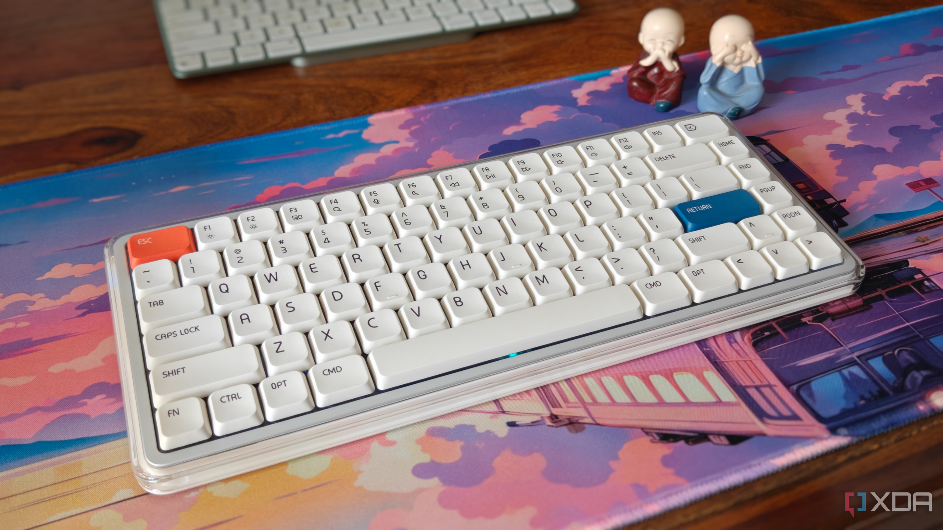 Close-up of a white mechanical keyboard on a deskmat on a brown desk