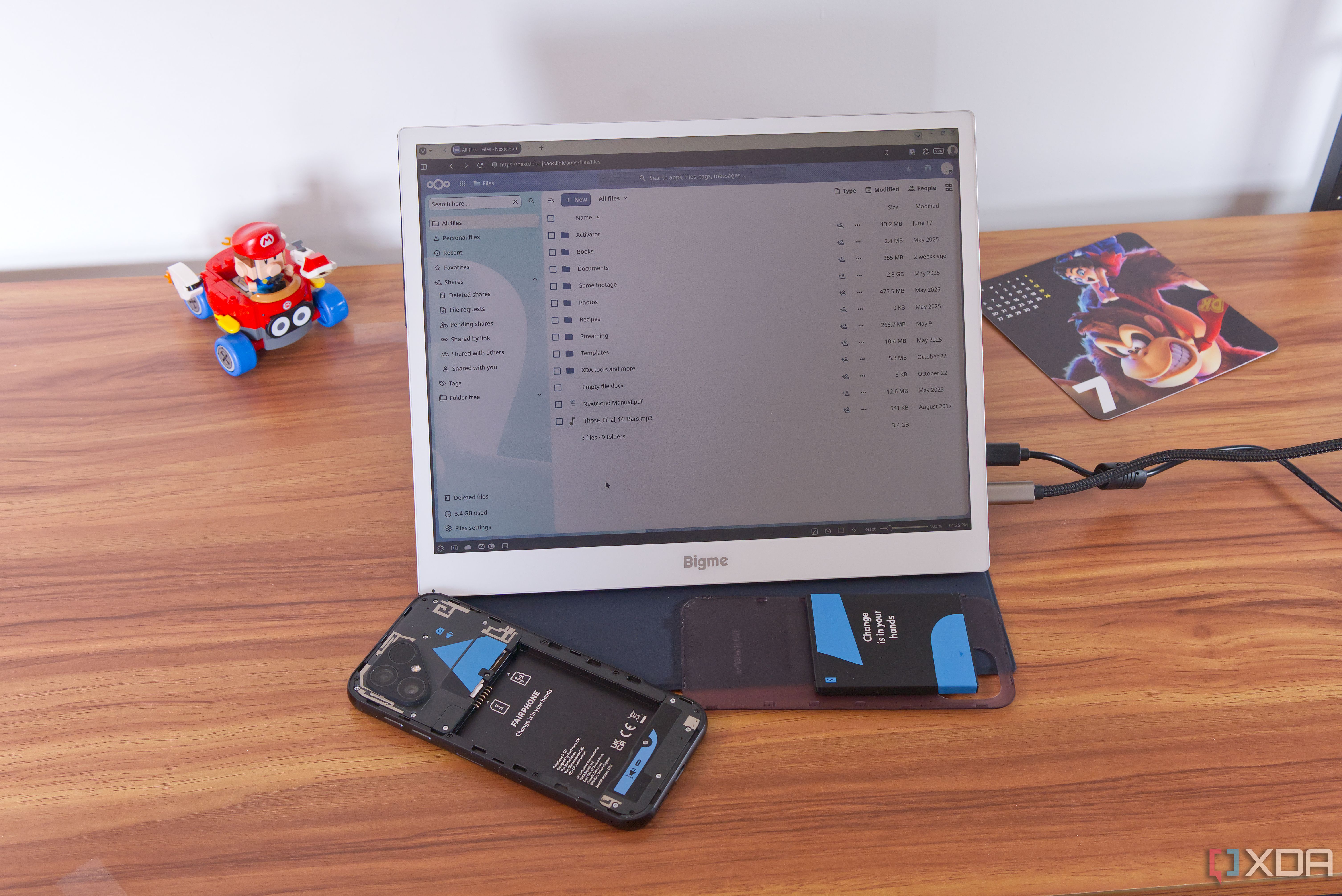 An E ink display showing a fiel list in Nextcloud, next to a Fairphone 5 with the back cover and battery removed