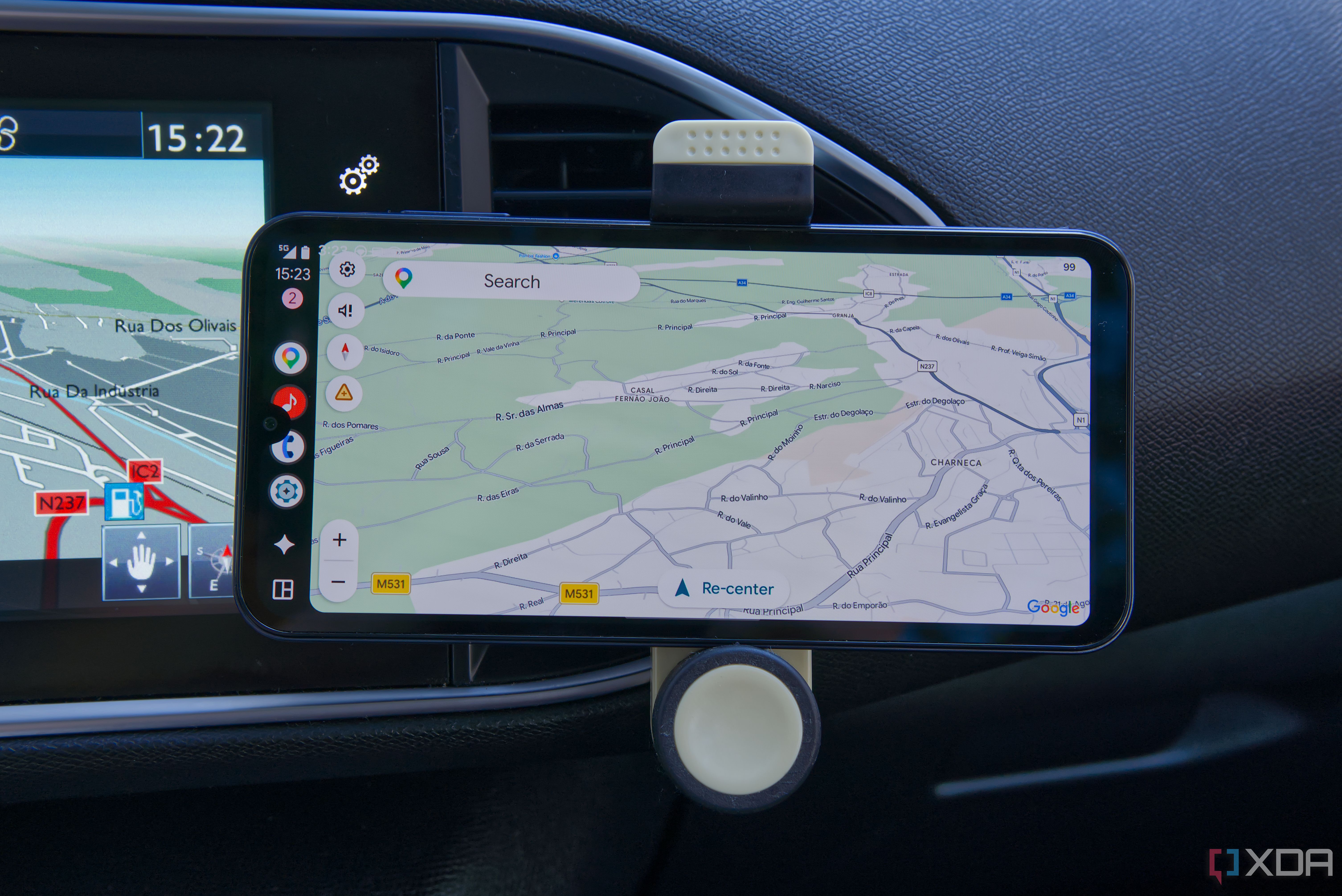 A phone showing Google Maps in Android Auto, with a built-in cart display showing its own navigation system in the background