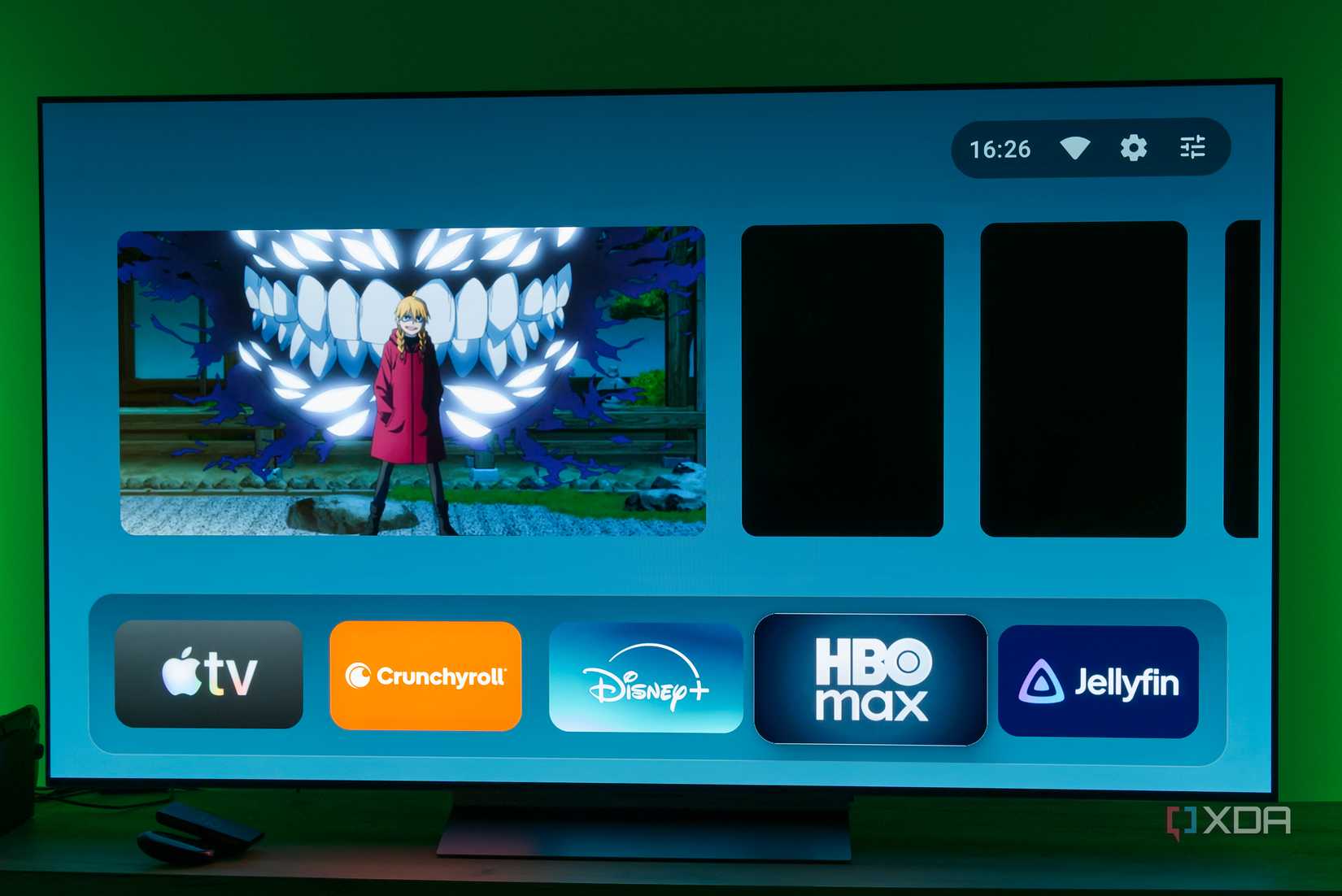 A TV displaying the AT4K homepage on Android TV with featured content cards, some of which are showing empty black space