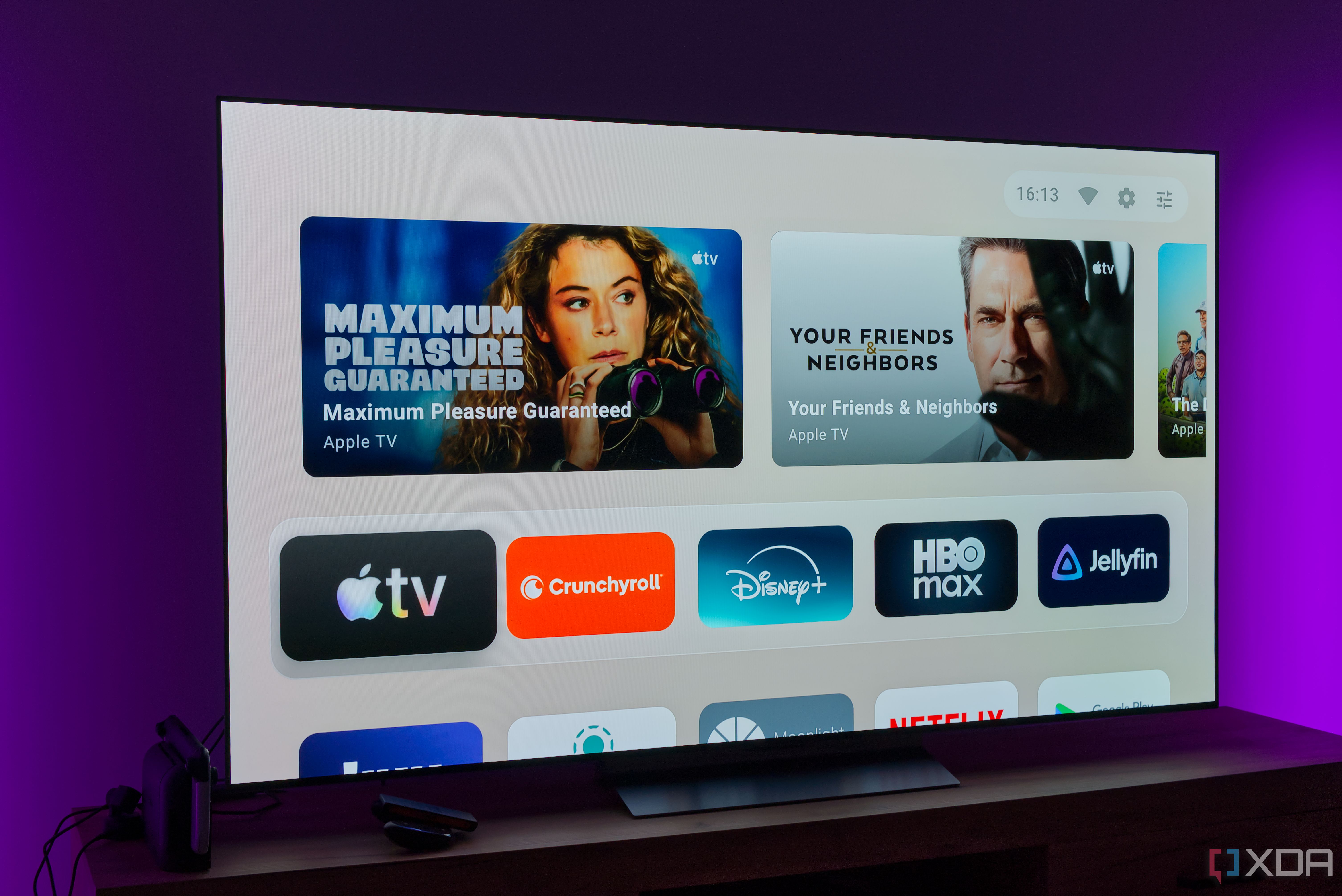 A TV showing the default home page on the AT4K Launcher, showing featured cards and favorite apps on a light background