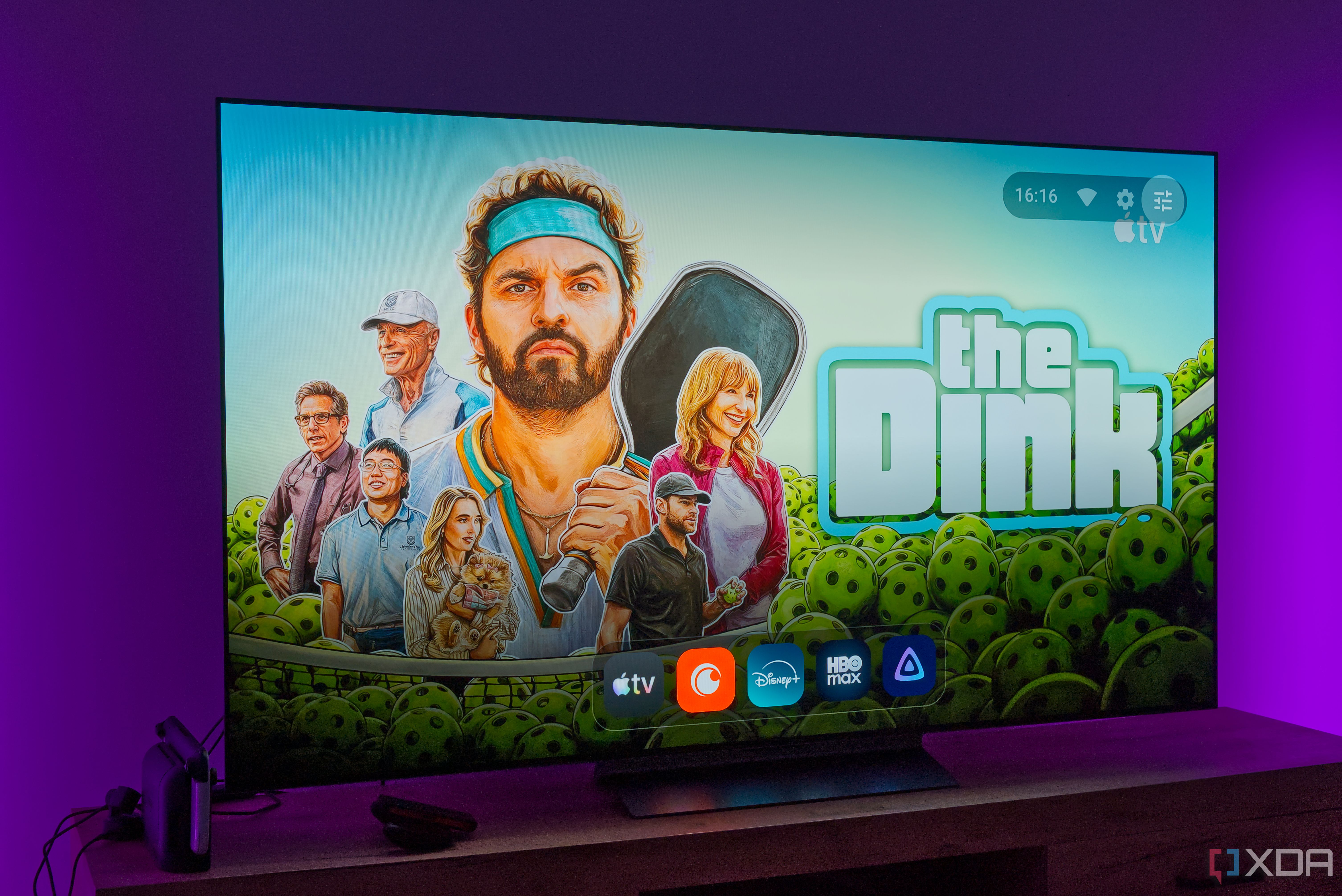 A TV displaying the homepage for AT4K Launcher on Android TV, with a full-screen wallpaper based on recommended content and a dock showing favorite apps in miniature size