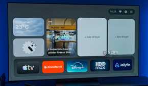 A TV displaying the homepage for AT4K Launcher for Android TV, with a small weather widget, a small analog clock widget, and one full-size RSS feed widget for XDA. Two widget slots are left open