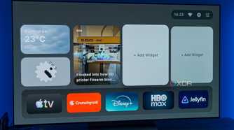 A TV displaying the homepage for AT4K Launcher for Android TV, with a small weather widget, a small analog clock widget, and one full-size RSS feed widget for XDA. Two widget slots are left open