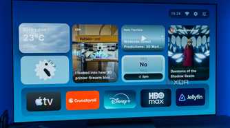 A TV displaying the homepage for AT4K Launcher for Android TV, with a small weather widget, a small analog clock widget, one full-size RSS feed widget for XDA, a small podcast widget, a small "Yes or no" spinner, and a "continue watching" card