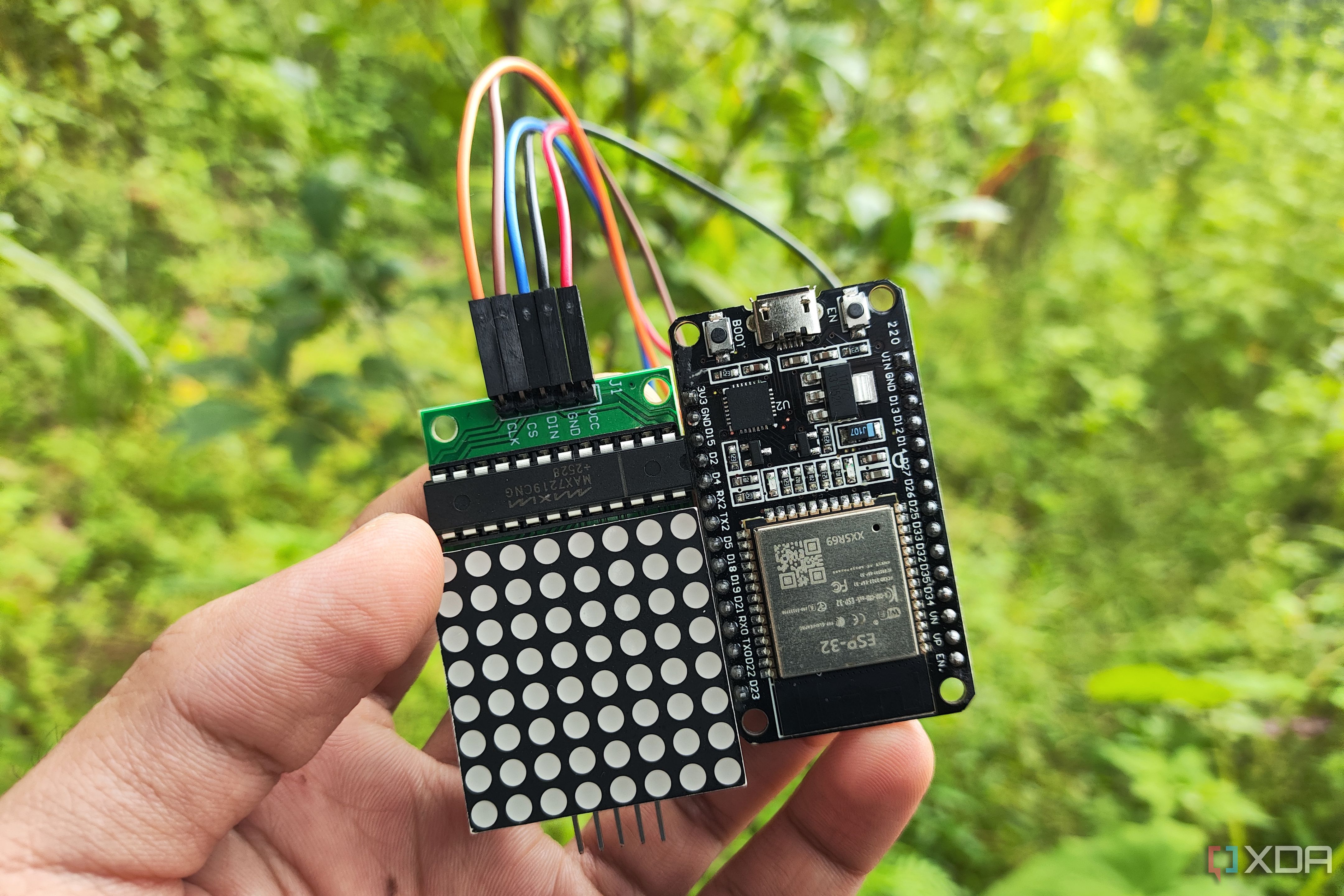 A person holding an ESP32 connected to a matrix display