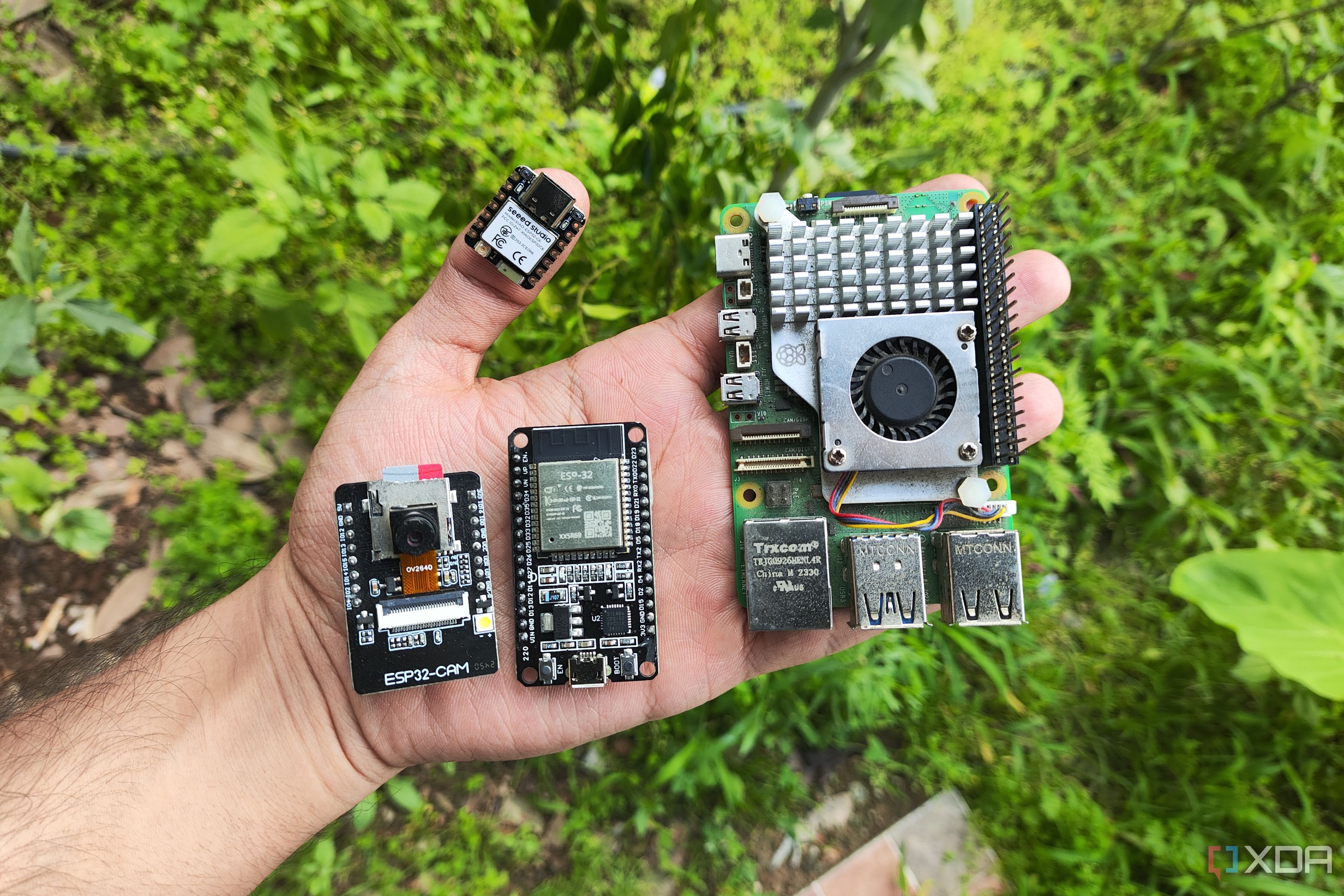 A person holding a Raspberry Pi and a bunch of ESP32 boards