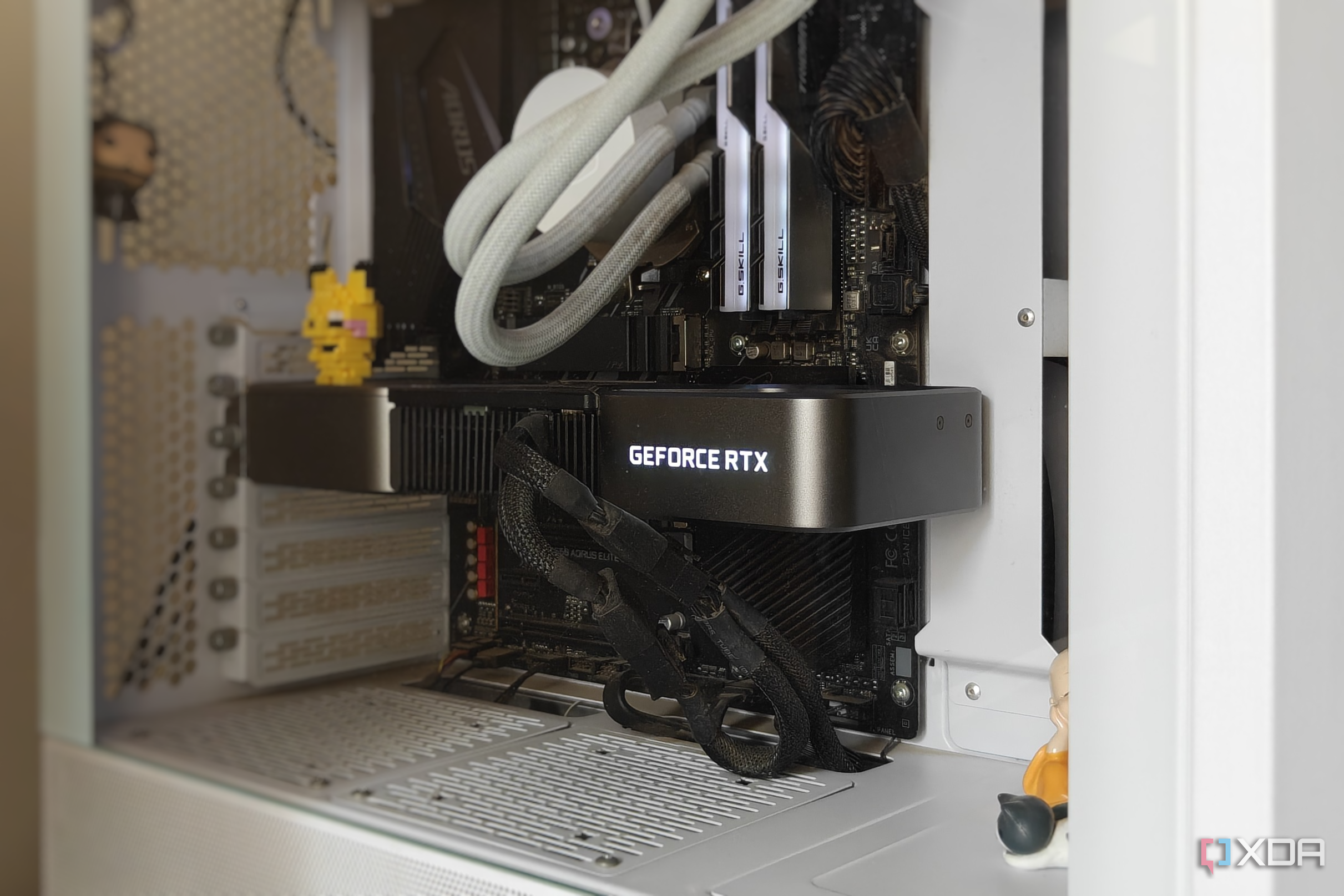 A white gaming PC showing a graphics card and other parts with some figurines