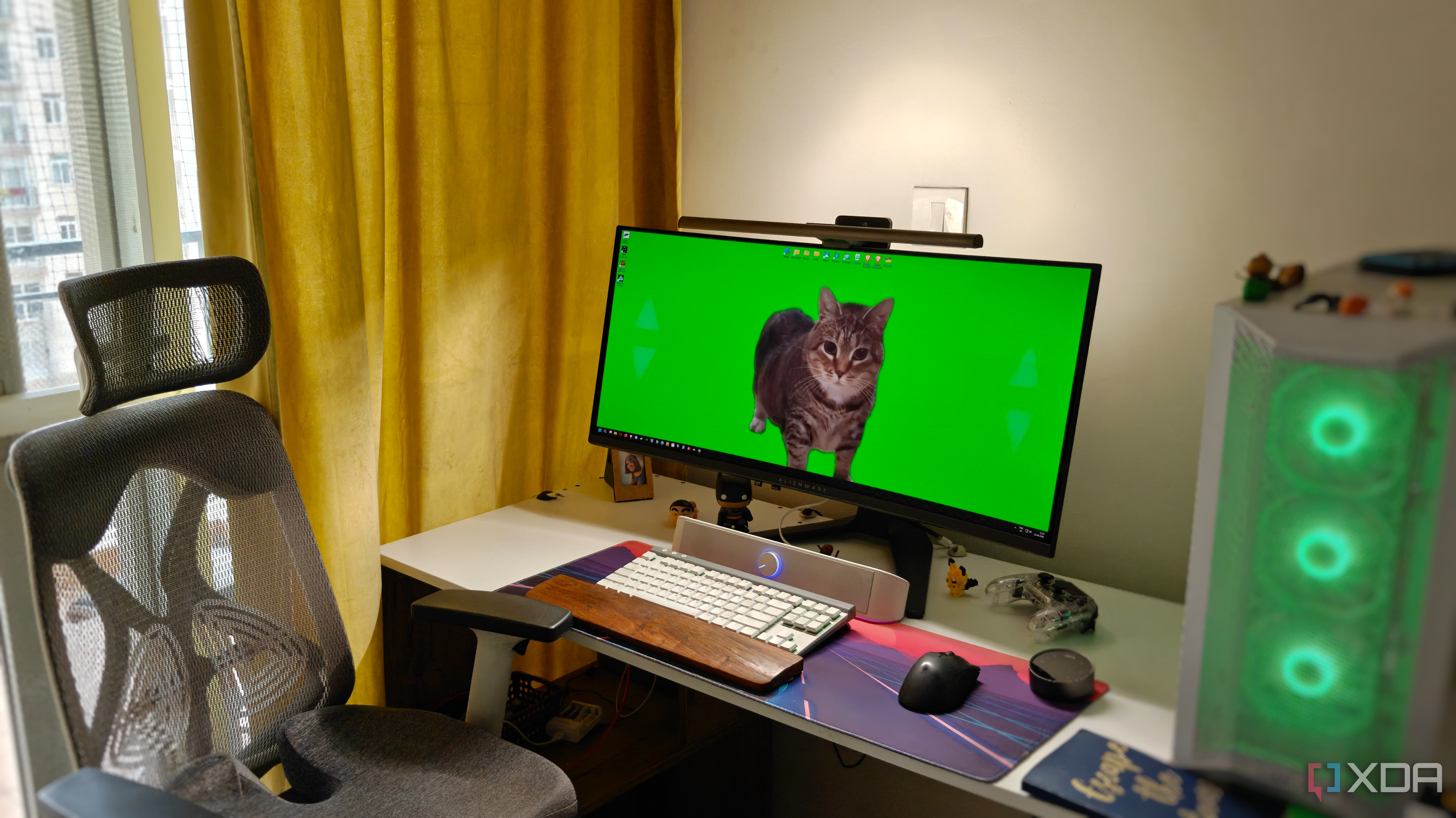 A gaming PC setup showing an ultrawide monitor on a white desk next to a chair