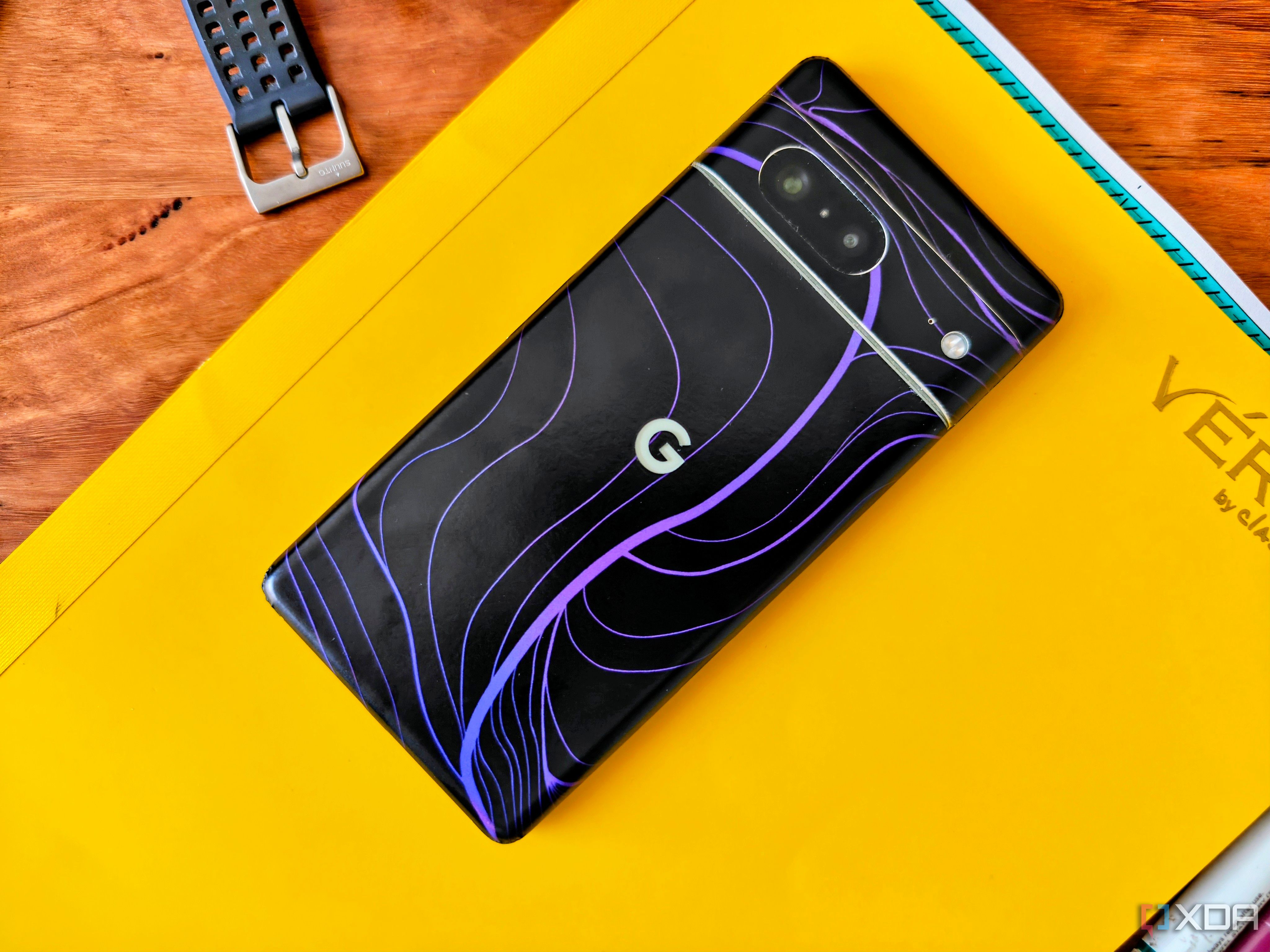 A Google Pixel 7 with a matte black wrap on a yellow notebook