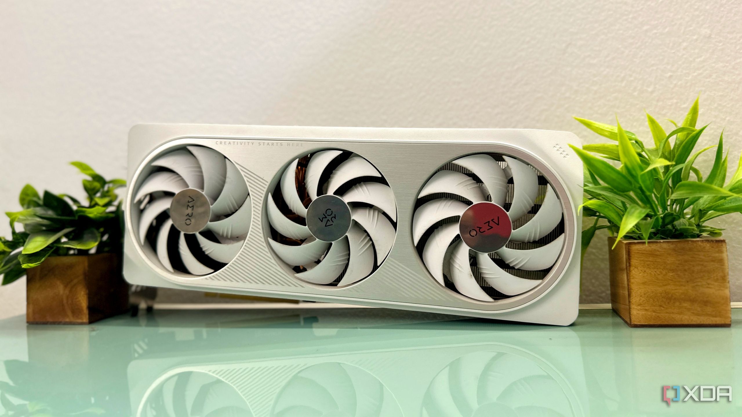 A white Nvidia GeForce RTX 4070 Ti GPU propped between two faux plants.